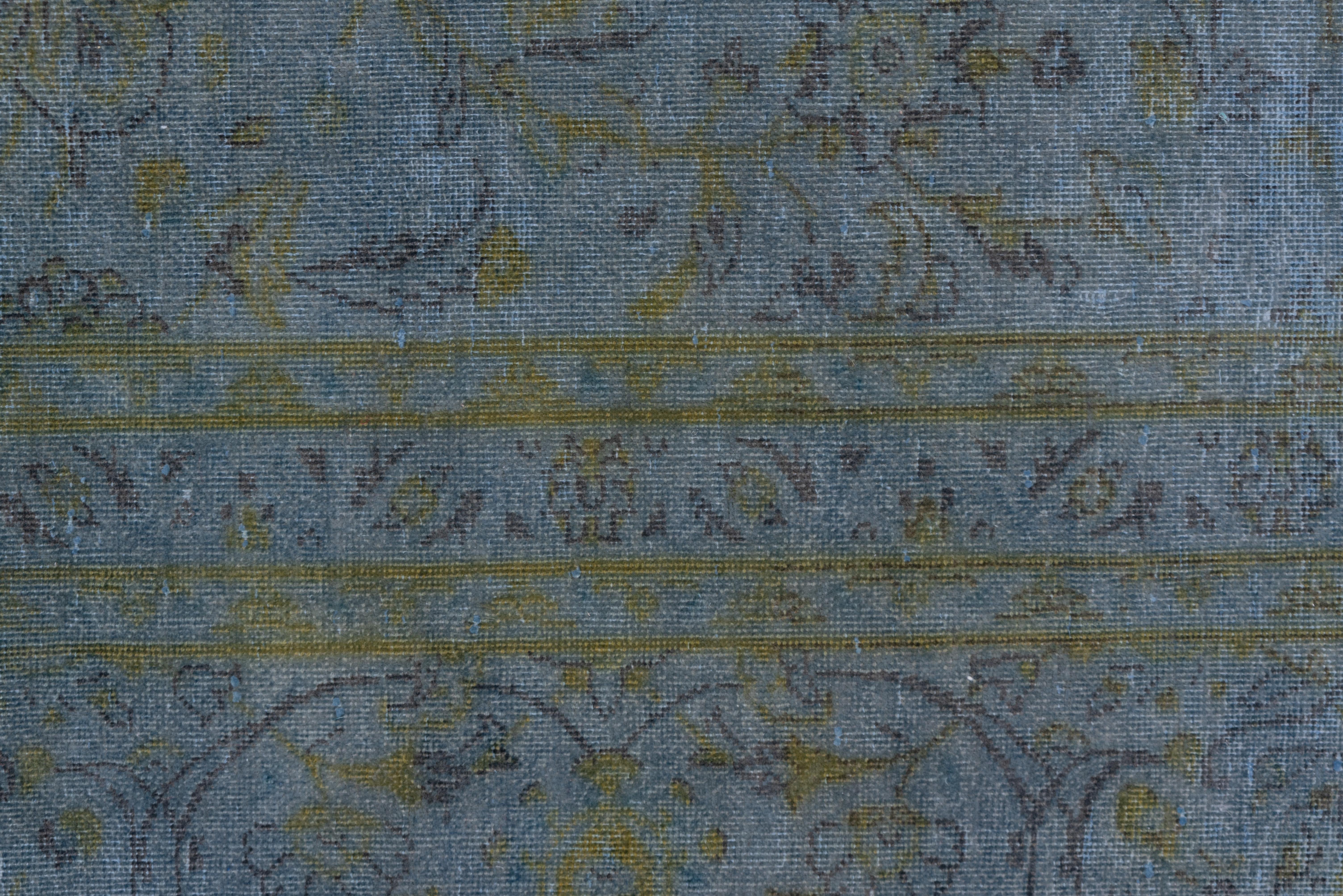 This modern and vintage rug is a light blue overdyed piece that lets the allover leaf and palmette  pattern organized around a central concave acanthus octogramme show through. Border of double rounded arabesques and carnations in the reserves.
