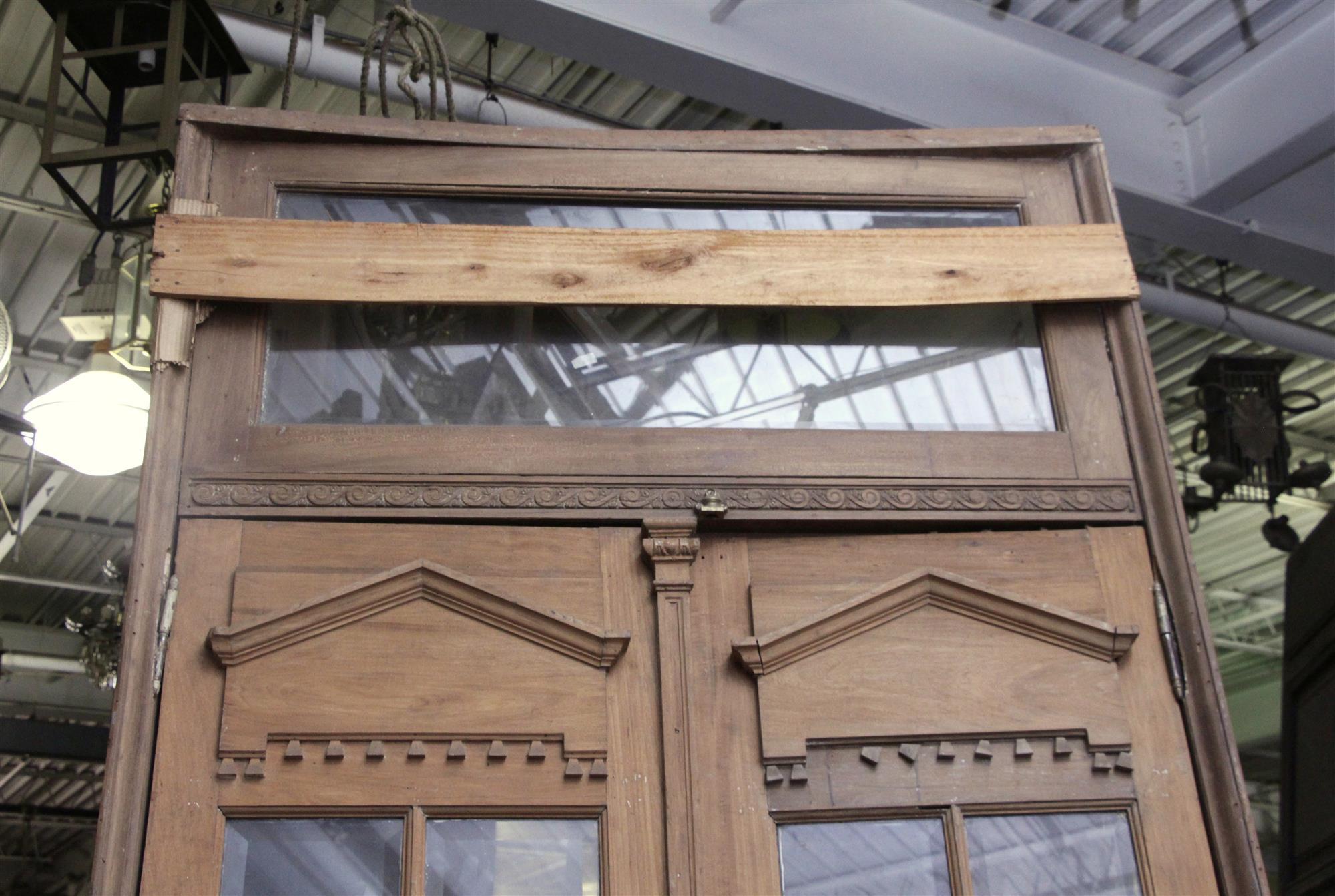 Spanish cedar 12 glass pane double doors with French beveled glass, windows and transom. The doors have beautiful carved details throughout the frame. Priced as a set. The dimensions are: 60 in. W x 130 in. H overall, doors 56 in. W x 98 in. H. This