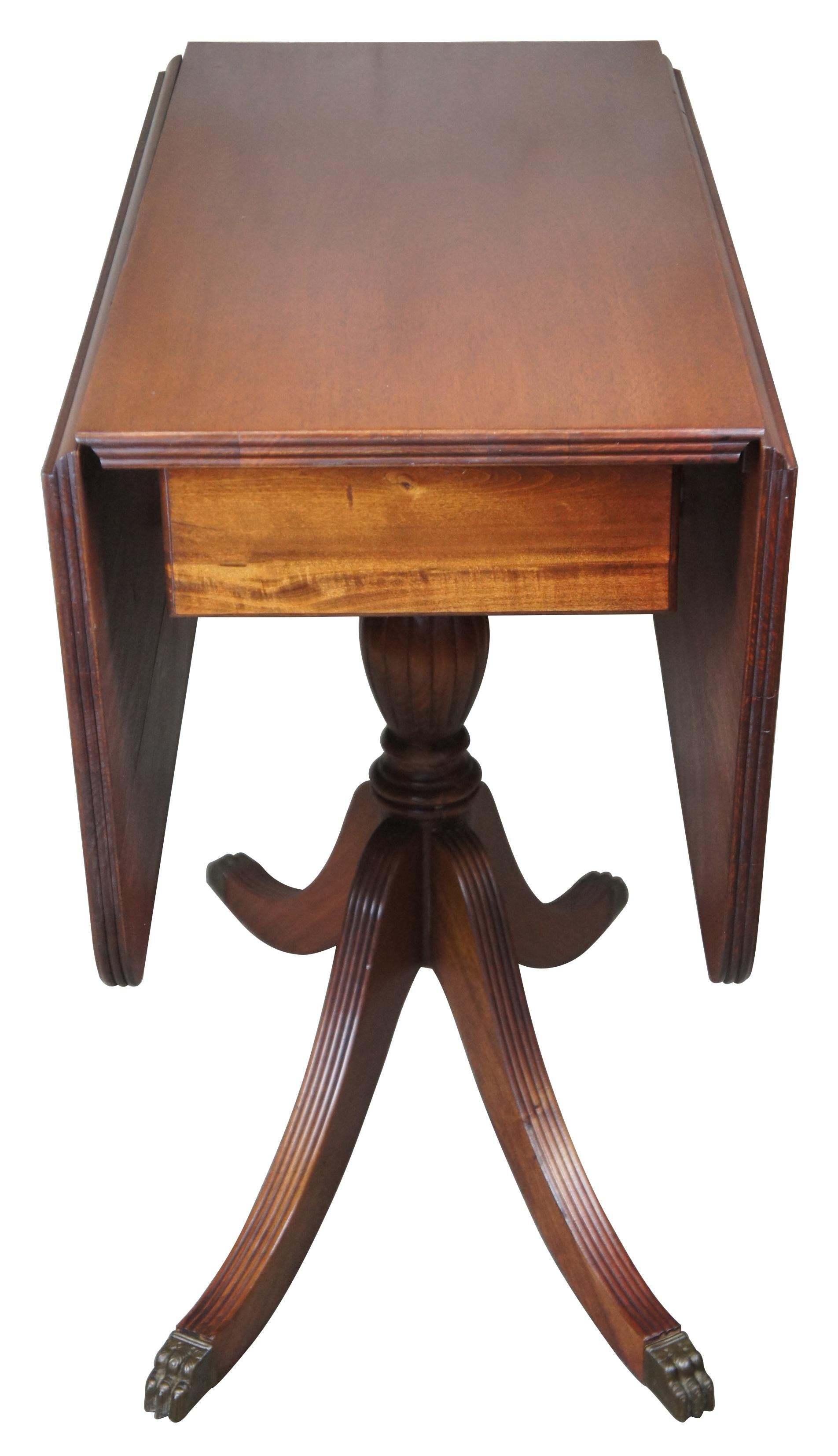 Circa 1940's Duncan Phyfe / Sheraton style mahogany drop leaf breakfast table or console. Features two drop leaves, turned pedestal and four sabre legs capped with brass paw feet. 

Folded - 16
