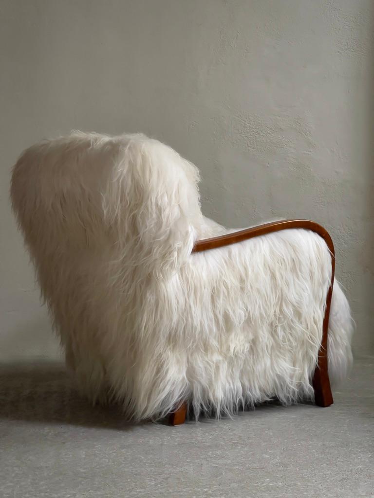 1940s Danish easy chair reupholstered in premium long haired Icelandic sheepskin with original kobber springs and historical refinish. A masterpiece from the realm of mid-century Danish furniture design. Crafted by a skilled Danish cabinet maker,