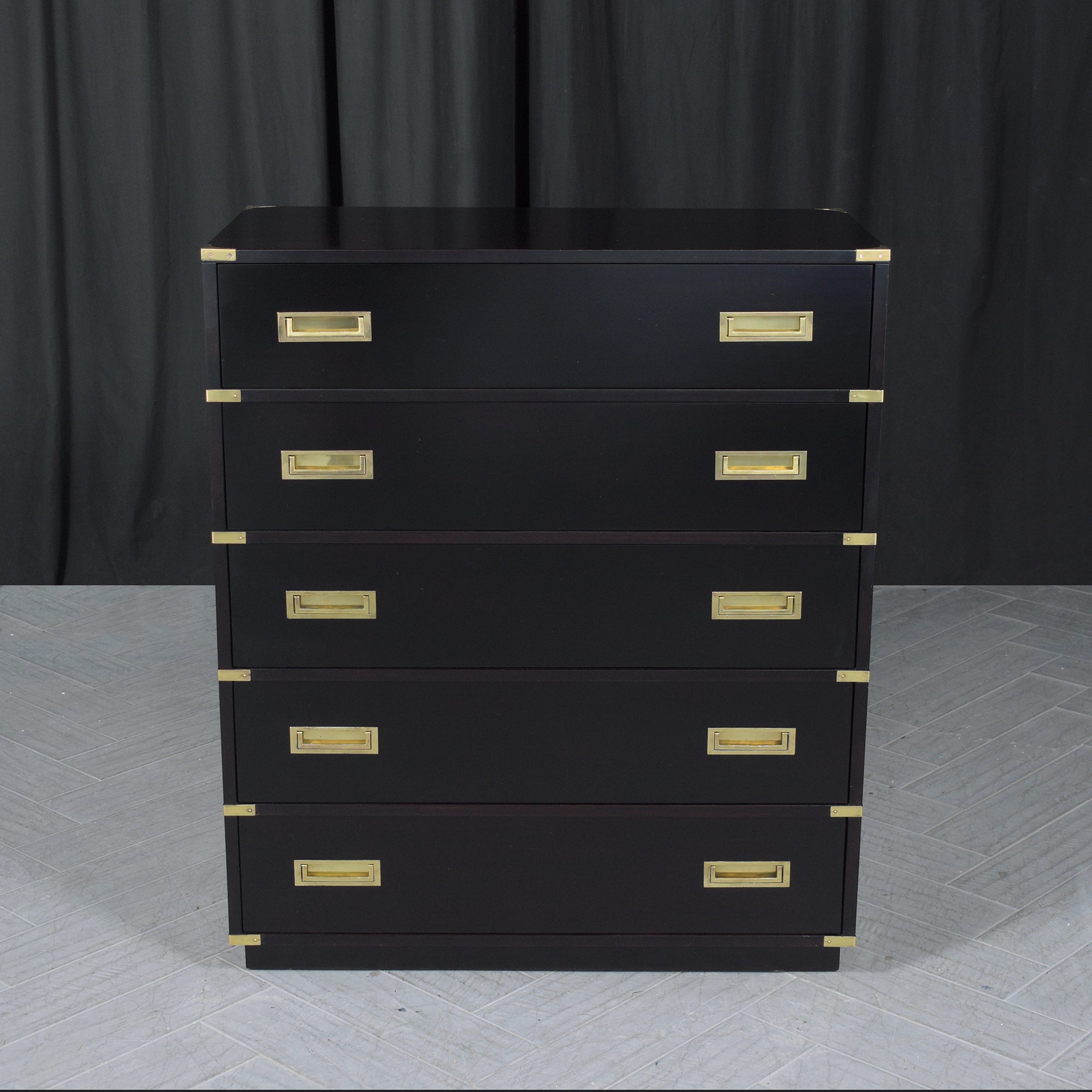 Dive into the captivating blend of historical elegance and modern sophistication with our Mid-Century Campaign Tall Chest of Drawers. Crafted from the finest mahogany wood, this exquisite piece showcases a striking ebonized black lacquer finish,