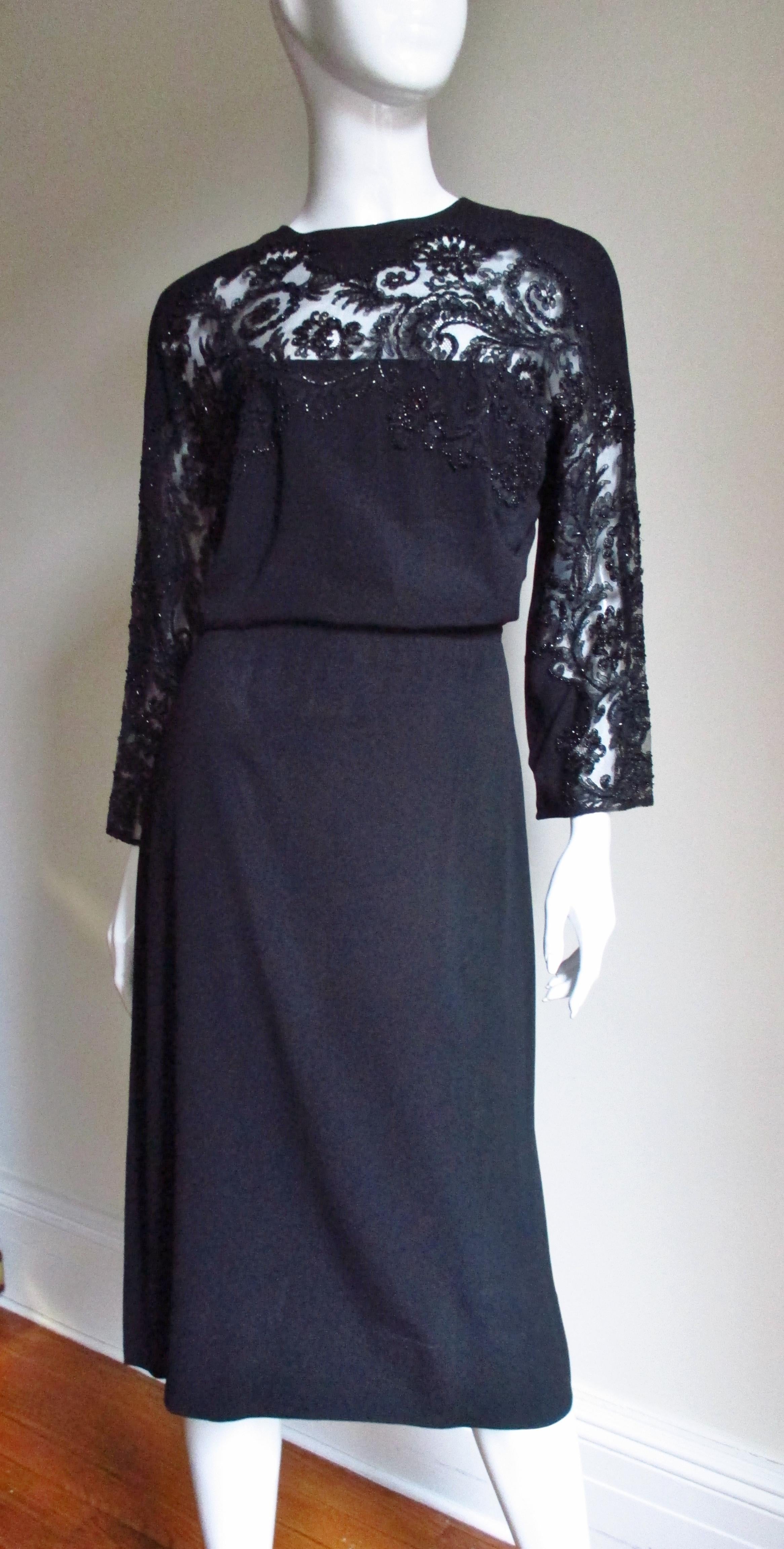A beautiful black silk 1940s dress by Eisenberg Originals. It has a crew neckline, long sleeves and a stunning richly detailed glass seed beaded lace insert across the upper chest and along the front of the dolman sleeves. The skirt is slightly A