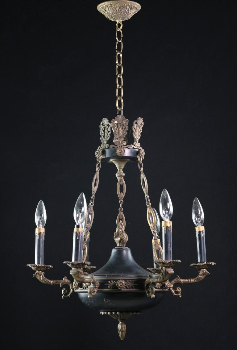 1940's Empire brass chandelier with center flame and four arms with two-tone coloring. It has gold details throughout including acanthus leaves and an acorn finial and the body has a black enamel finish. The price includes restoration. This can be