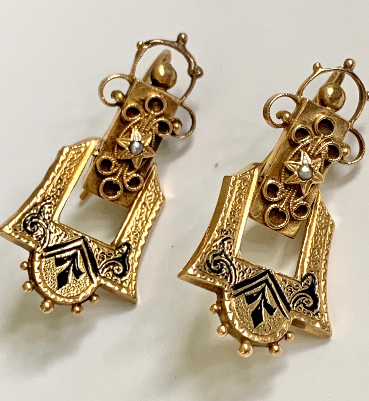 These beautifully enameled 14k yellow Gold earrings each feature one seed pearl in the center of a star on each earring drop.  Black enameling is featured throughout the top of each earring.  The closure is a shepherd's hook for added security. 