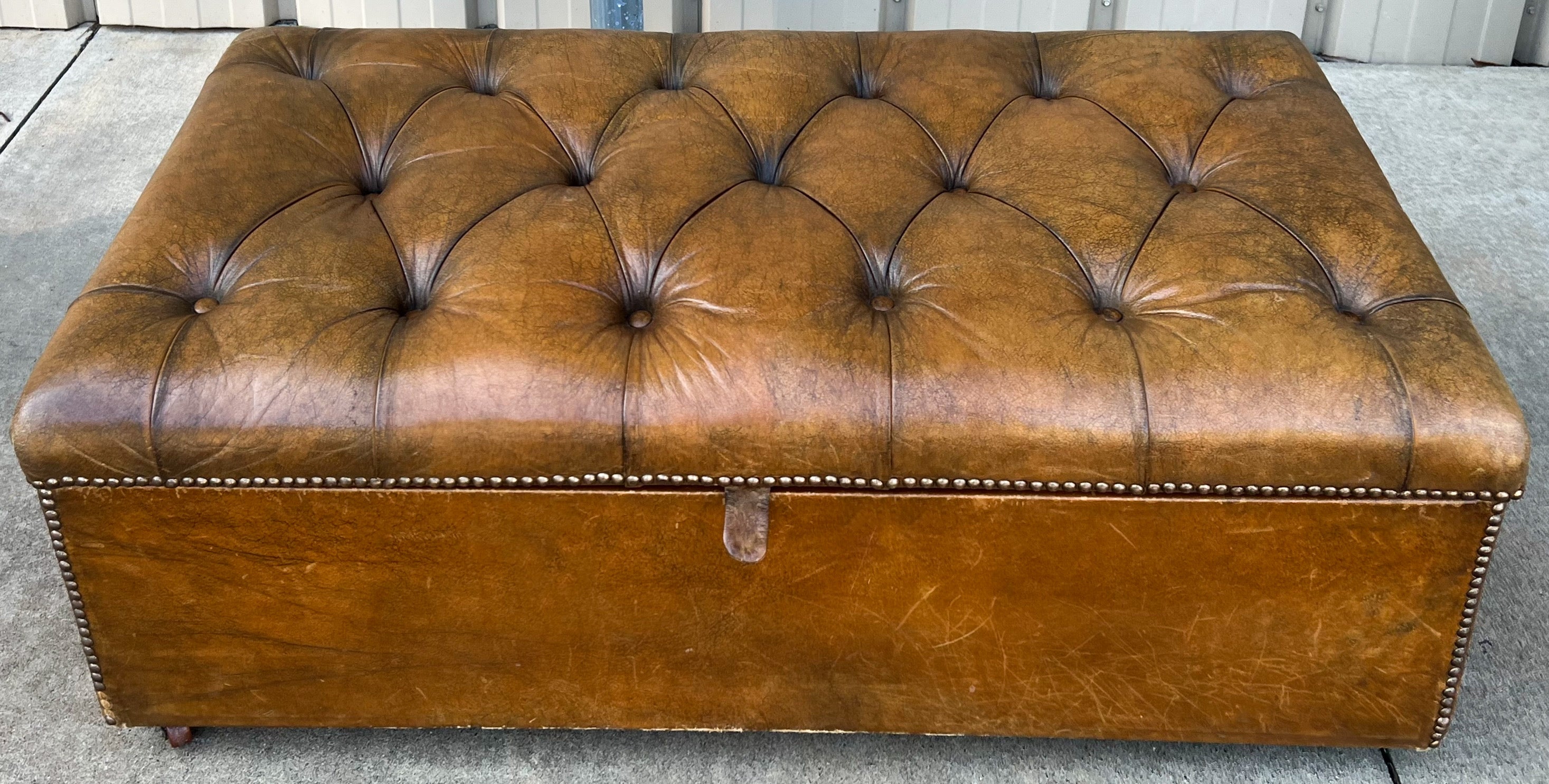 This is a 1940s English Chesterfield style tufted leather bench with storage. It is a wonderful piece with quite a bit of character. The storage will surely make it a family favorite.