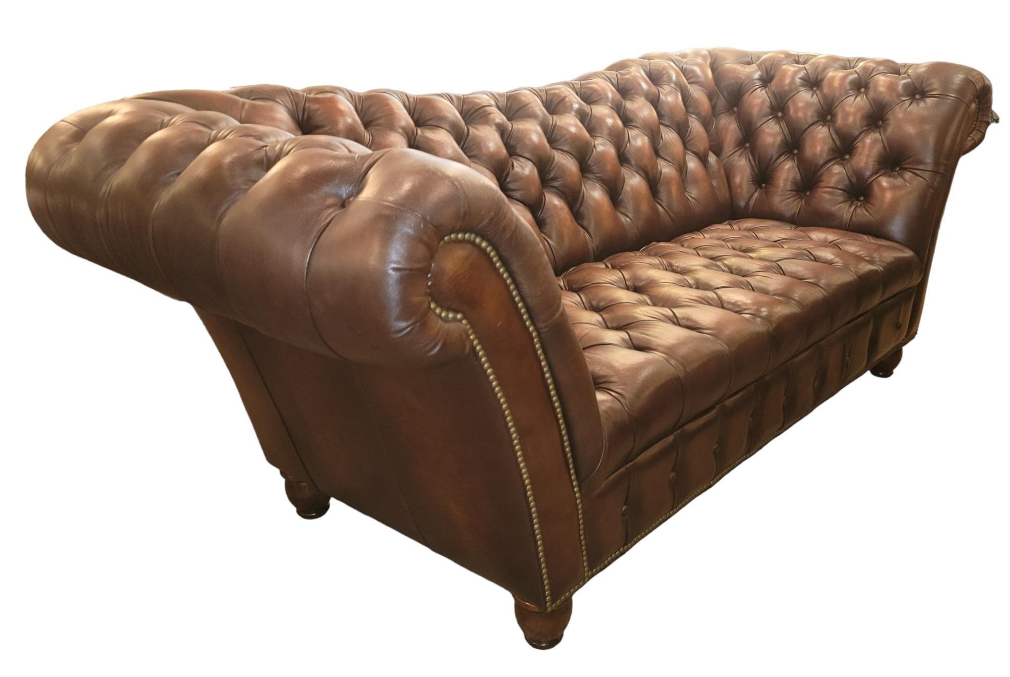 English reverse camel back tufted brown leather three seat sofa with wonderful, rolled arms with original buttons. The Brown leather is in great condition. Such a soft and comfortable seat design with soft supple seats.
