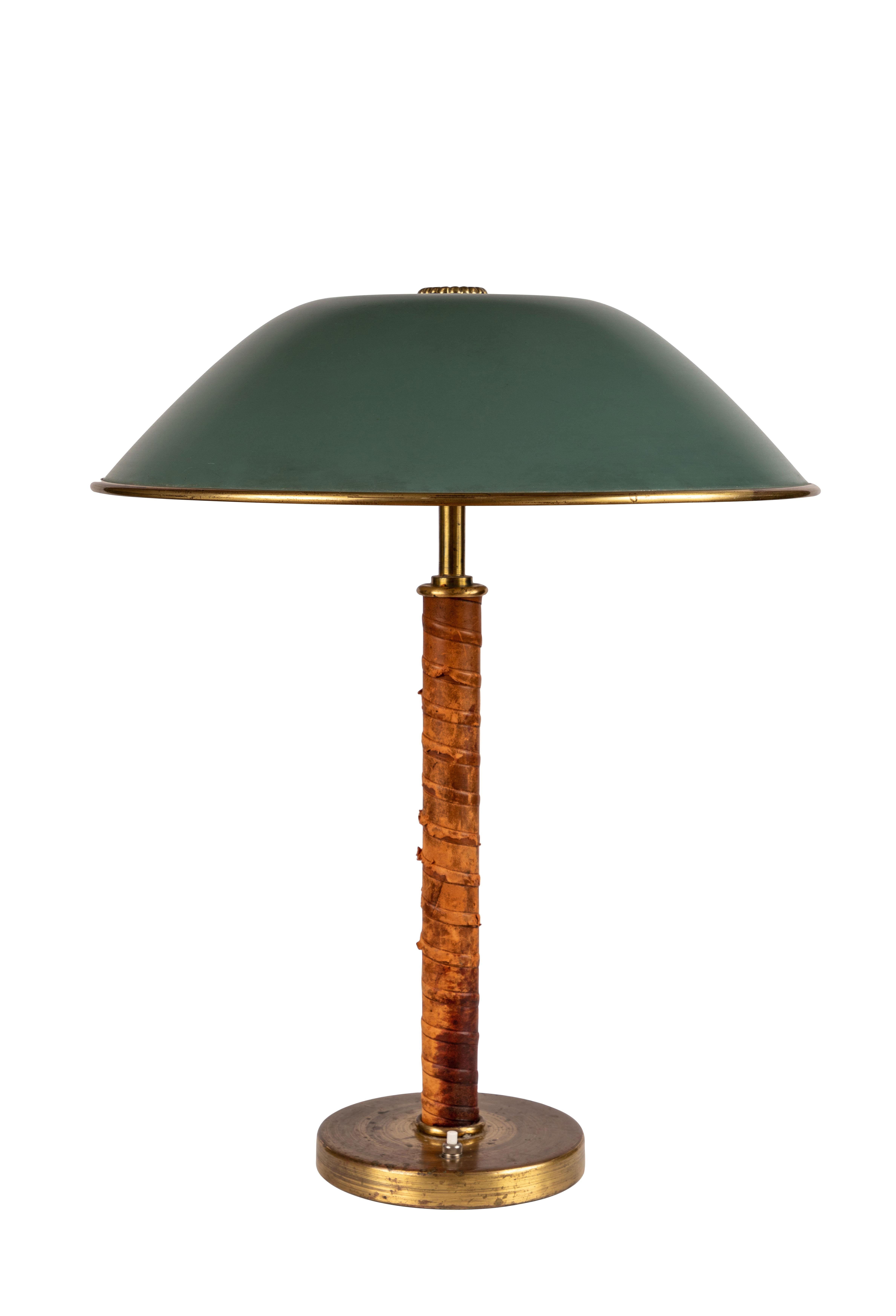 1940s Finnish brass and leather table lamp. Executed in green painted metal, brass and beautifully distressed but sound leather wrapping. Unmarked and designer unknown, but highly reminiscent of the early designs of Paavo Tynell for Taito Oy. An