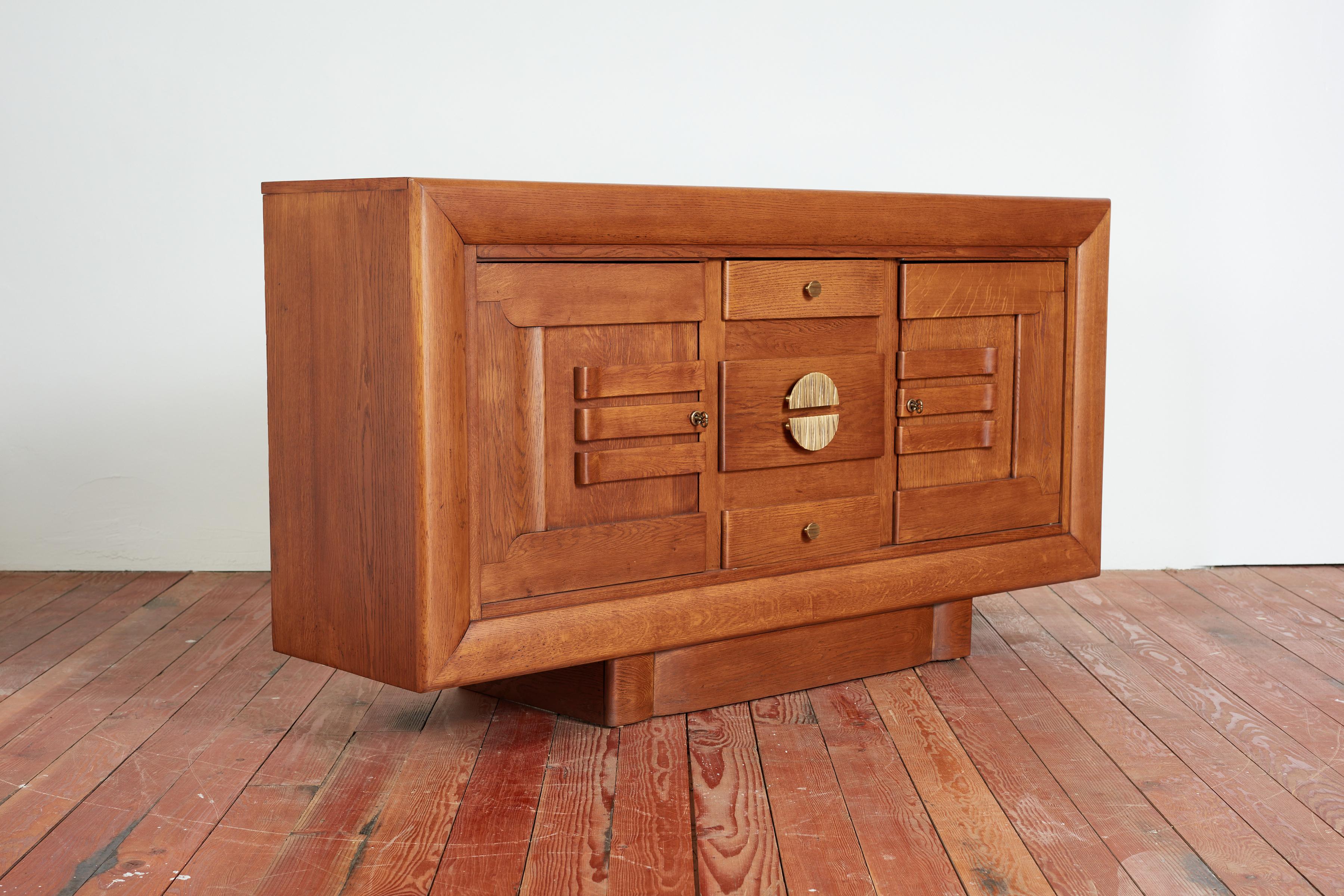 Gorgeous 1940's French Oak Sideboard floating on a plinth with intricate solid bronze hardware. 
Oak has wonderful rich patina and doors open on each side with drawers down the center. 
Impressive in scale - 
France, 1940s