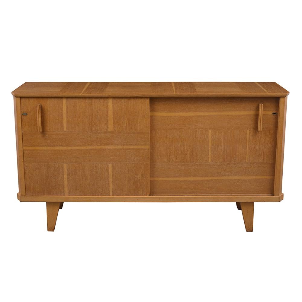 This 1940's Art Deco Buffet is made out of elmwood with an elegant symmetrical design and has been fully restored. The cabinet features two sliding doors with carved handles, the interior has three pull-out drawers on the top left side with one wood
