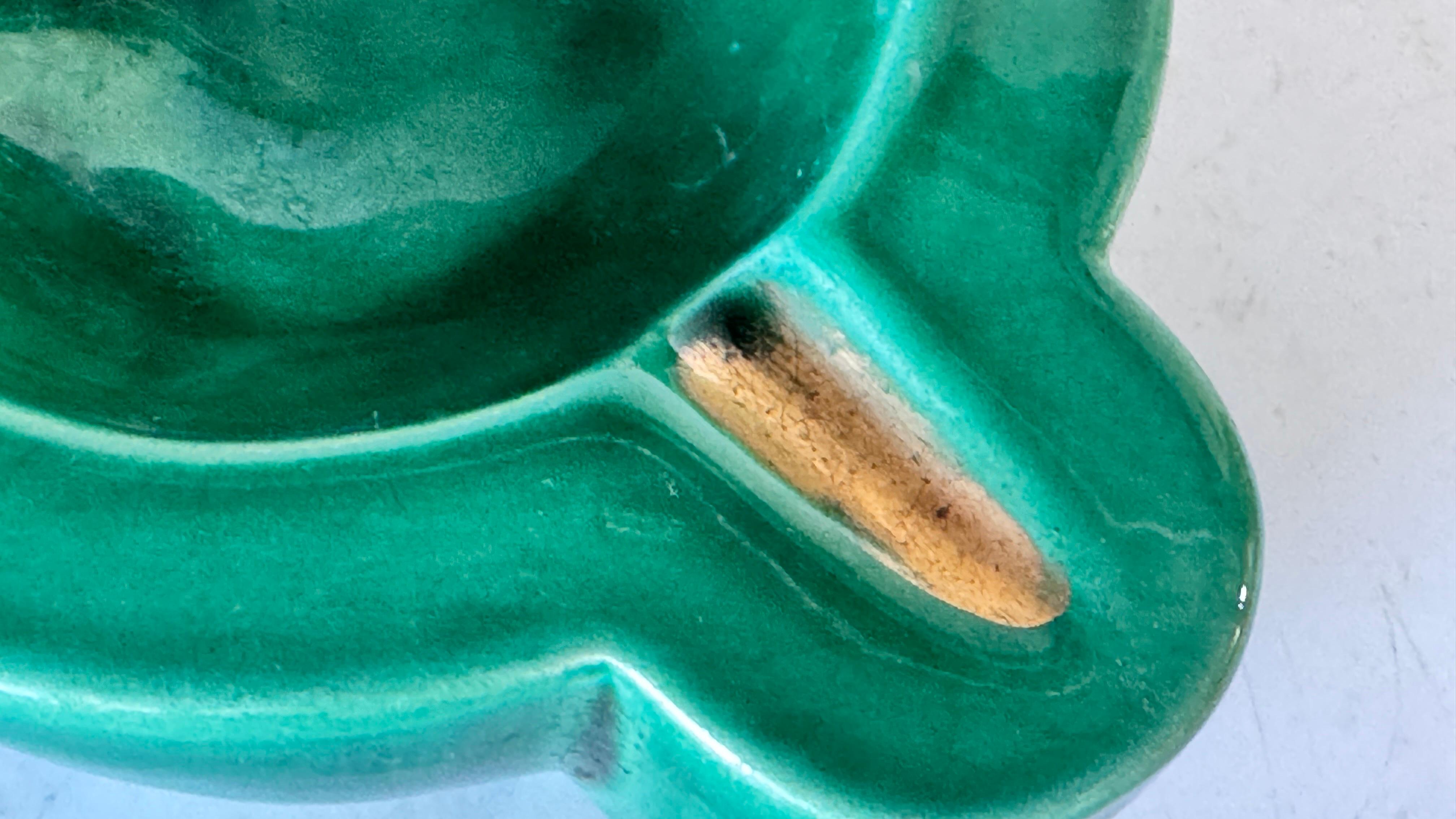 1940s French Art Deco Green Ceramic Ashtray with Gilded Details, Four Cigarette Rests

Description:
This elegant Art Deco ceramic ashtray, crafted in France in the 1940s, beautifully embodies the bold yet refined style of the period. Featuring a