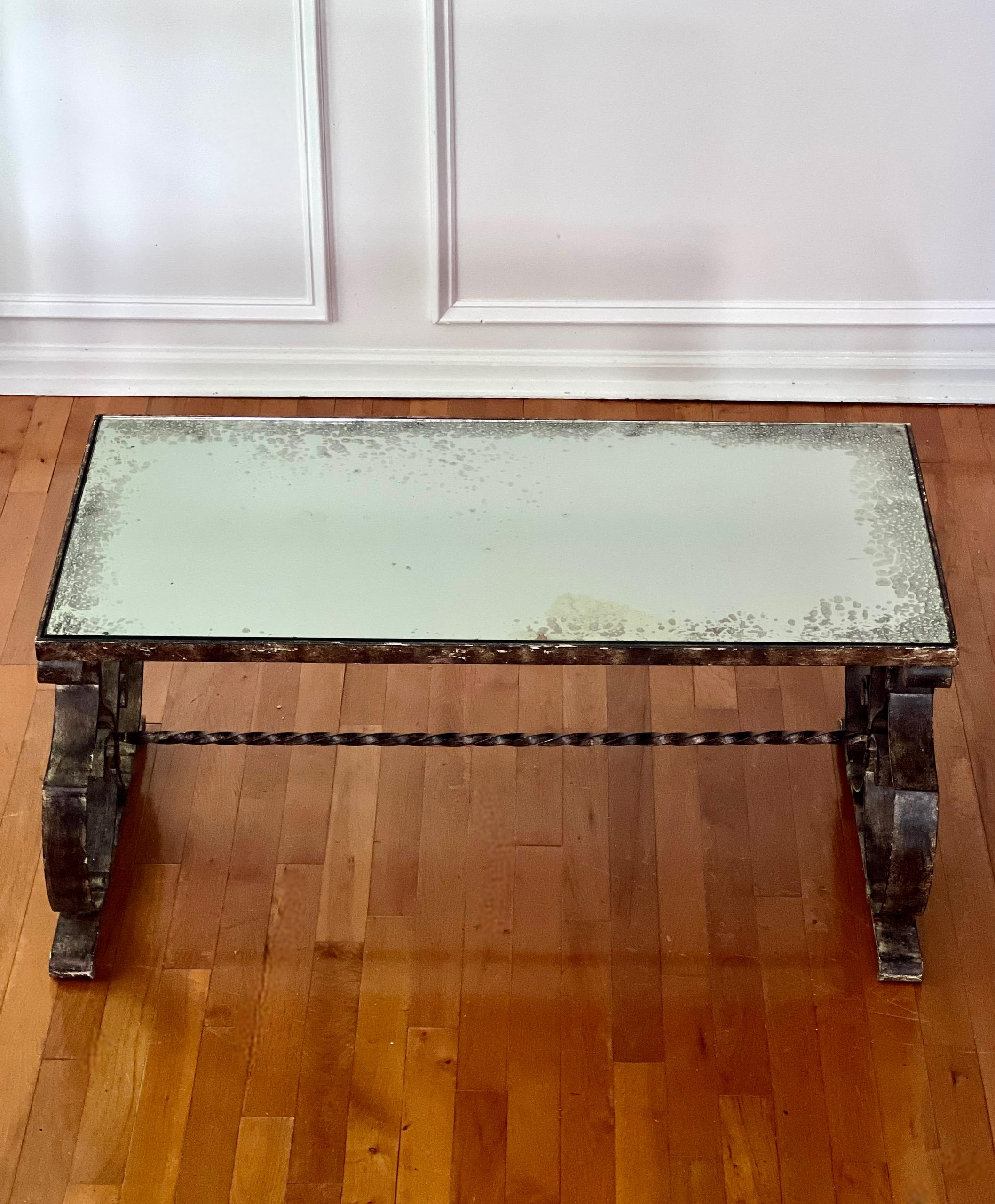 Impresionante mesa de centro de hierro forjado Art Decó francés de la década de 1940, a la manera de Raymond Subes, con tapa de espejo eglomizado.   La parte superior del espejo tiene mucho carácter, con un borde moteado que le confiere un aspecto