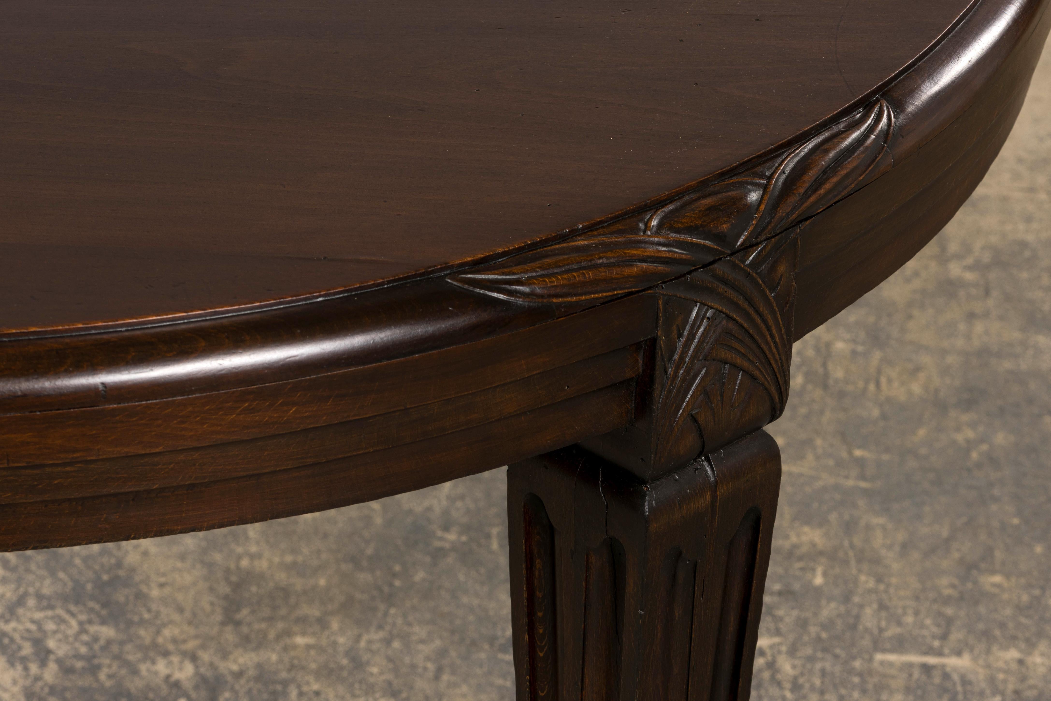 An elegant 1940s French Art Deco dining table, sourced from Provence, France. Handcrafted from solid maple, the table features an oval top adorned with traditional floral carvings. It has been structurally revised and refinished in a rich dark brown