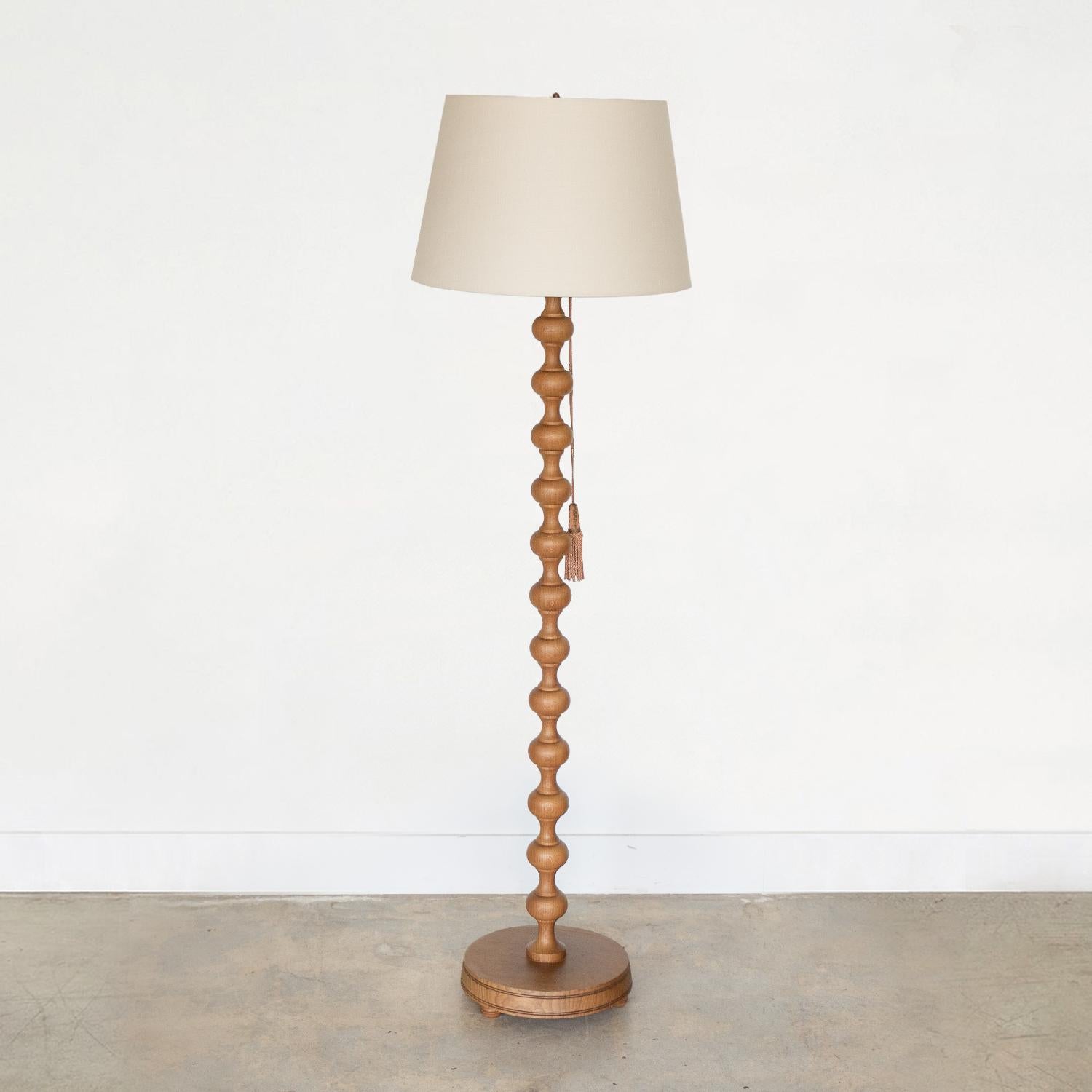 Beautiful carved bobbin wood floor lamp from France, 1940's. Great light wood finish and original velvet pull tassel to turn light on and off. Newly re-wired and new linen shade.