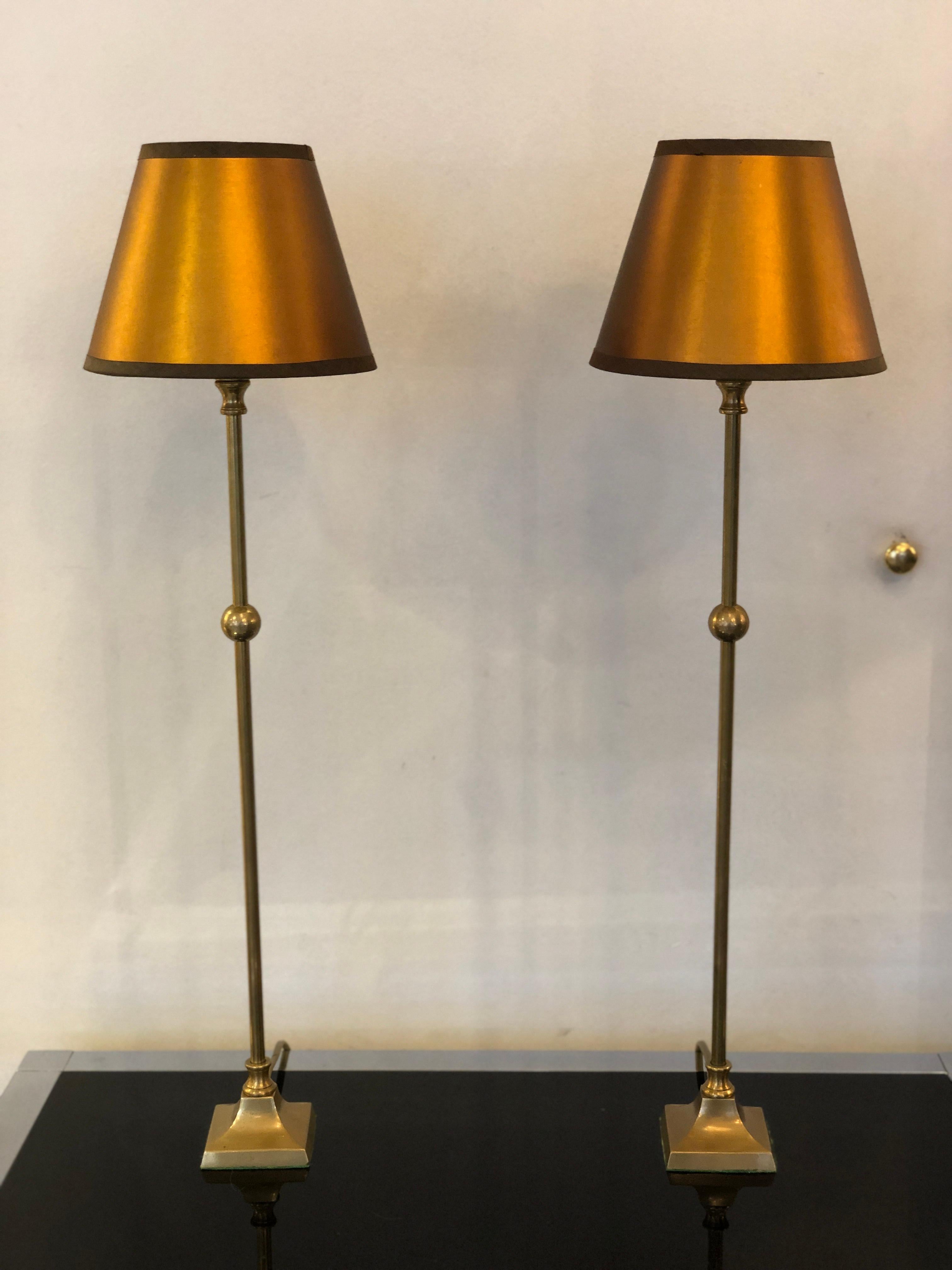 1940s French brass table lamps in their original patina.
A pair of thin and tall table lamps with small squared base and small bronze upholstery lampshades.
These lamps, for they particular size, can be used in a variety of locations from the