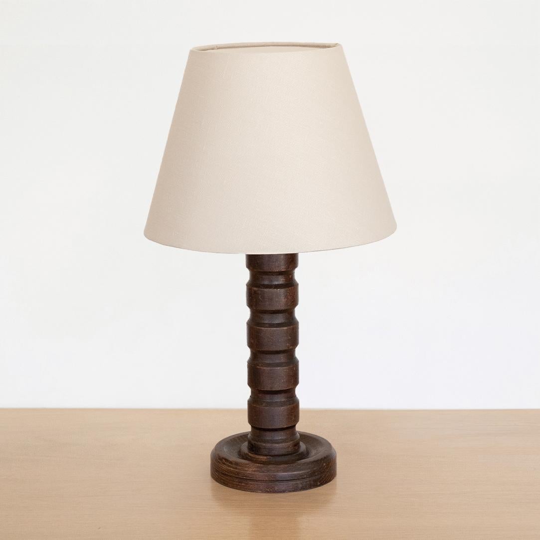 Large carved wood brutalist table lamp from France, 1940s. Beautiful thick carved ribbed detailing on wood stem with original dark wood finish. New ivory linen shade and newly re-wired.