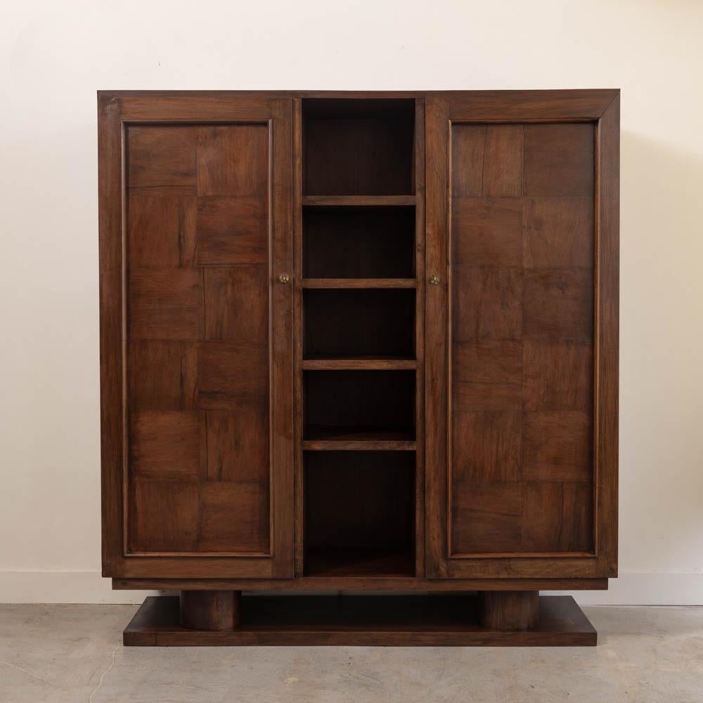 Incredible carved wood cabinet in the style of Charles Dudouyt from France, 1940s. Beautiful carved wood with parquet detail on two front doors and three interior shelves on each side. Four open center shelves. Original brass hardware with key to