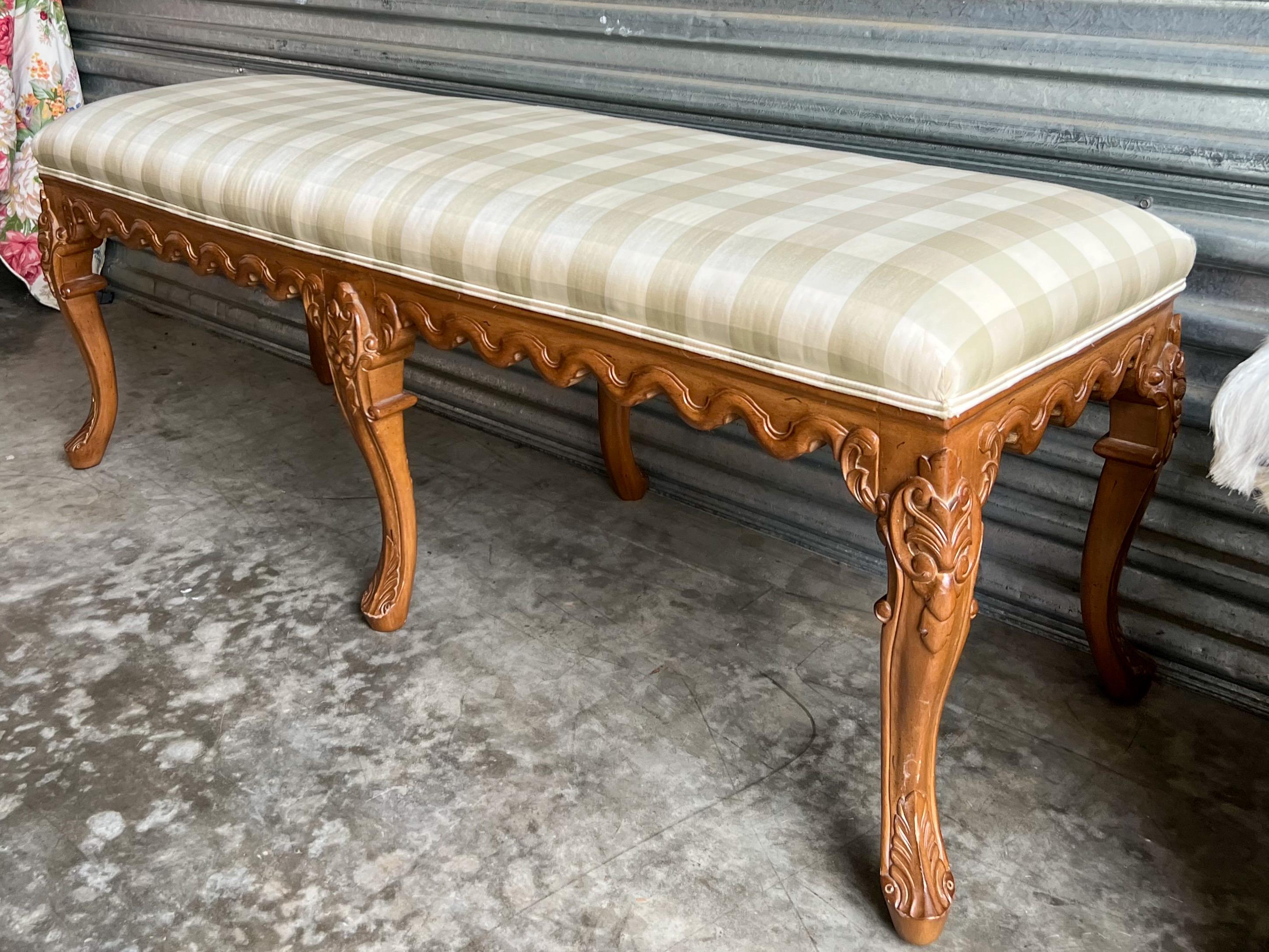This is a unique bench! It is a carved fruitwood French bench with 6 legs. The vintage fabric is a neutral silk with tonal checks. It is in very good condition. The bench itself most likely dates to the 40s. It is unmarked.
