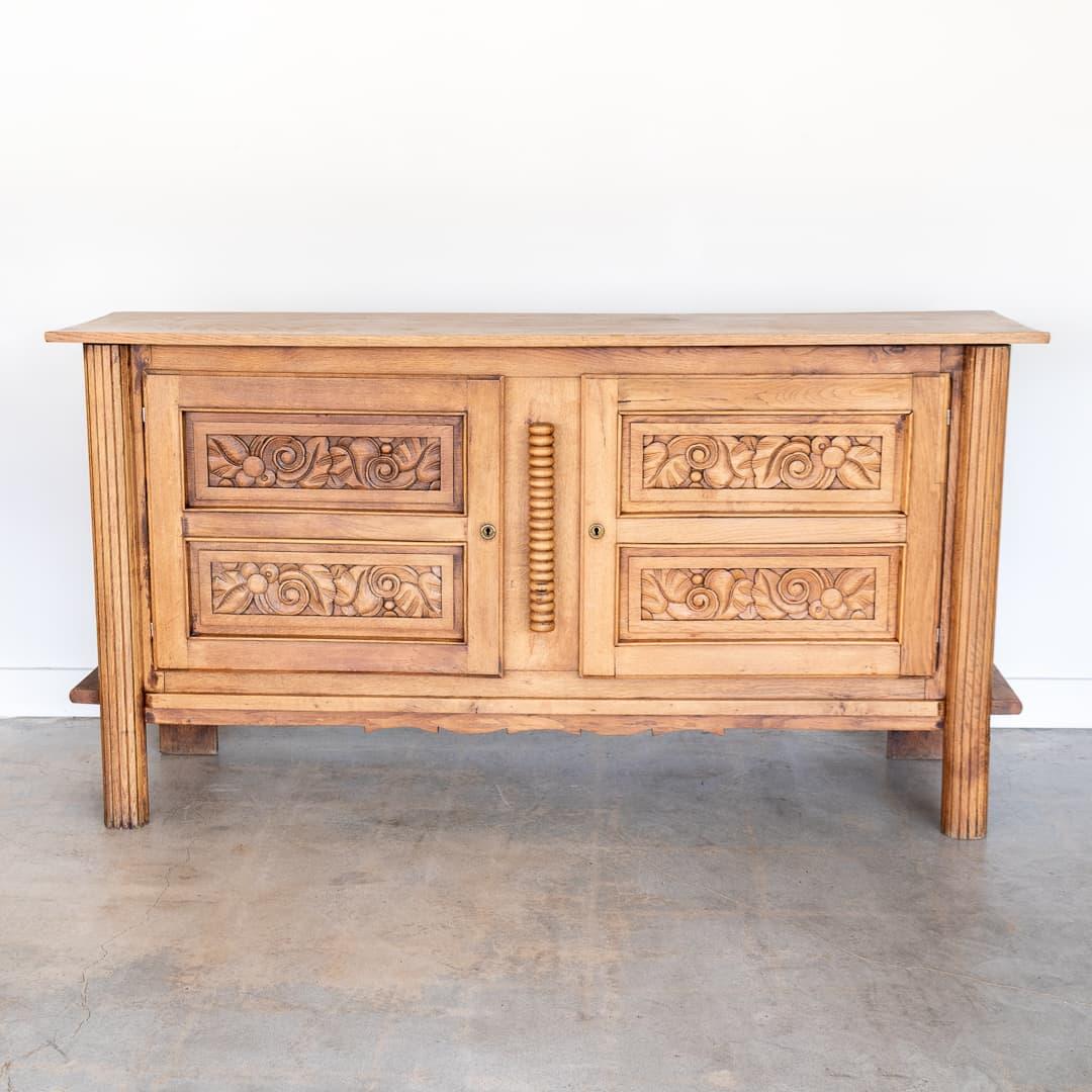 Stunning light oak cabinet from France, 1940's. Original light wood finish in nice vintage condition showing great age and patina to wood. Beautiful ornate carved detail on doors and legs. Two interior shelves and two drawers in original condition.