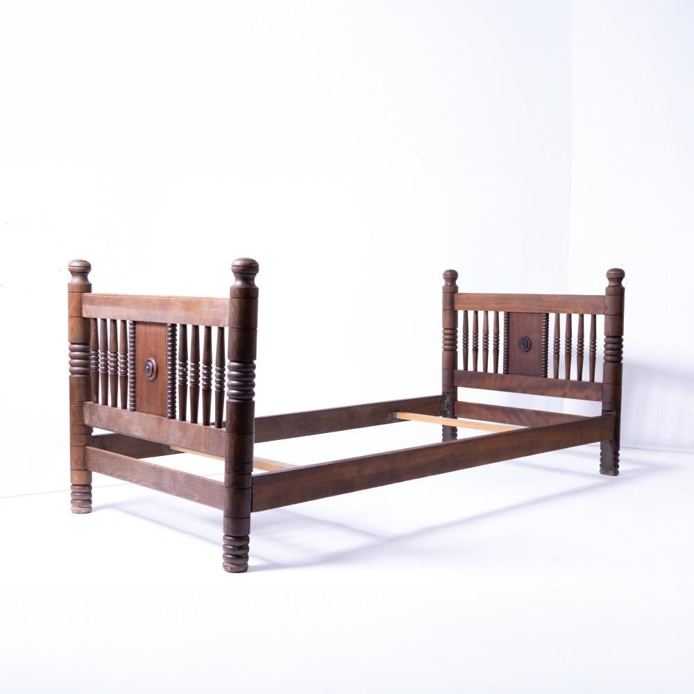 Incredible and rare vintage twin bed frame by Charles Dudouyt, circa 1940's France. 
Long oak wood frame with carved spindle and circle detail. Original finish shows nice age and patina. Includes side rails and two slats. Beautiful statement piece.