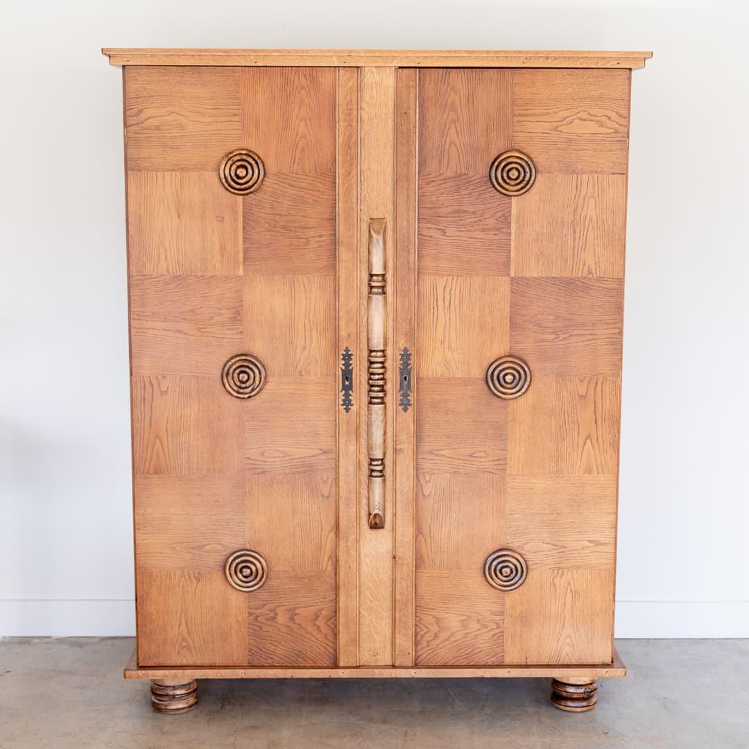 Incredible carved wood storage cabinet by Charles Dudouyt from France, 1940s. Beautiful carved wood circle detail on two front doors with checkered wood pattern design. Original brass hardware with keys to lock each side. Cabinet rests on four