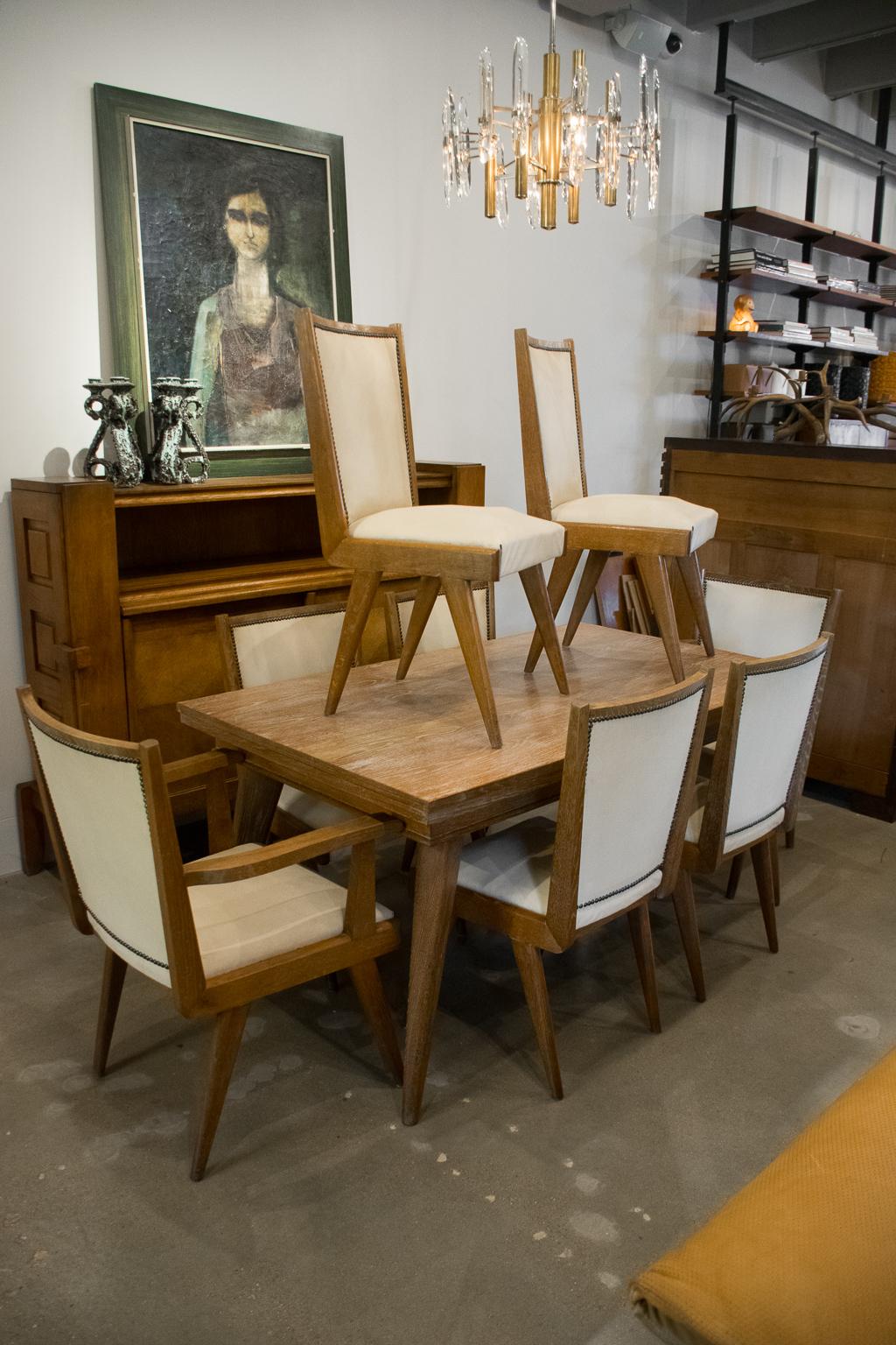 Finely crafted dining room set includes extendable dining table with six side chairs and two arm chairs, attributed to Charles Dudouyt (1885-1946). The set is heavy, constructed of solid French oak in a cerused or limed finish, typical of Dudouyt.