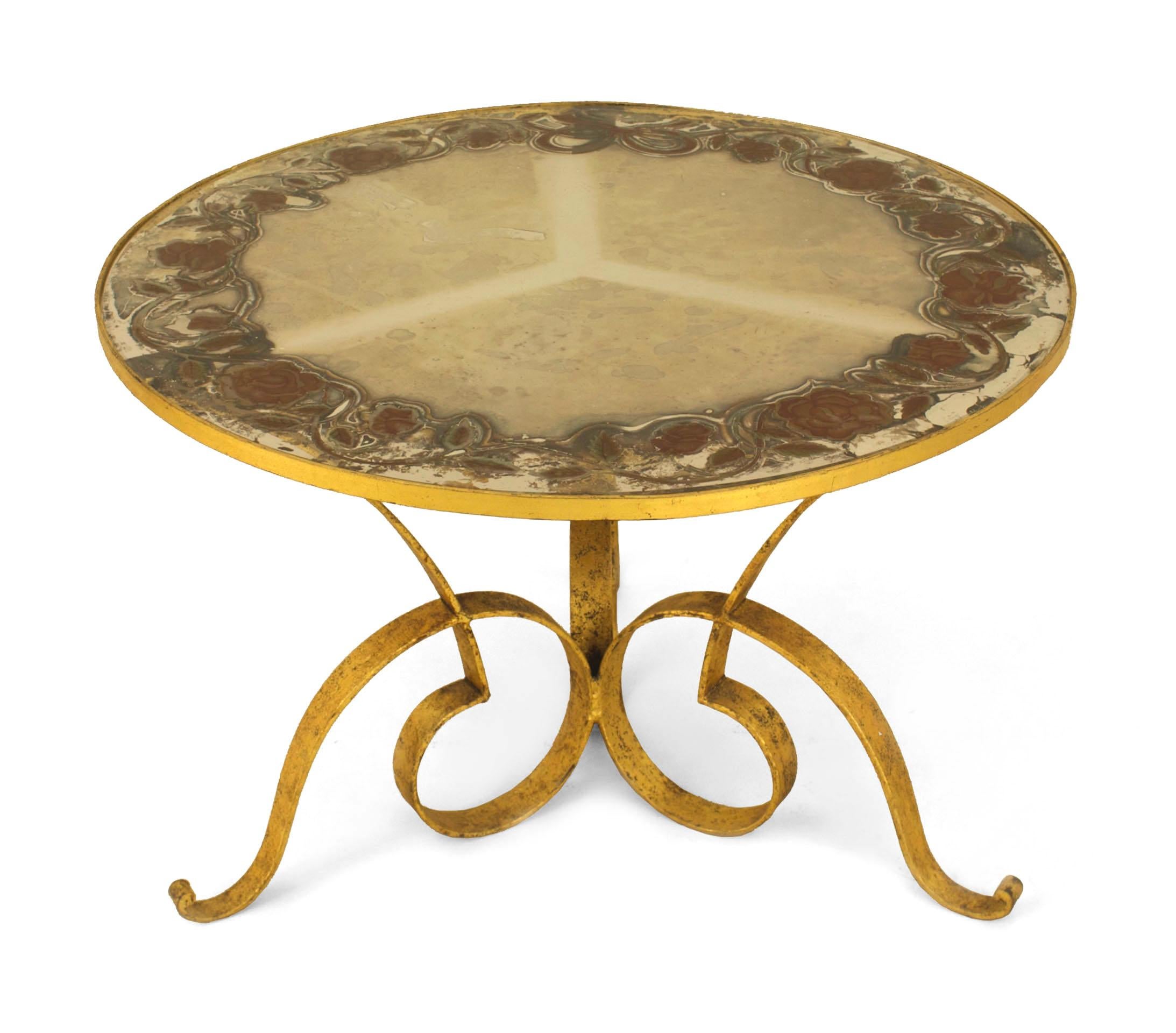 French 1940's gilded hand-hammered iron coffee table with triple scroll design base supporting a circular black opaque glass top.
