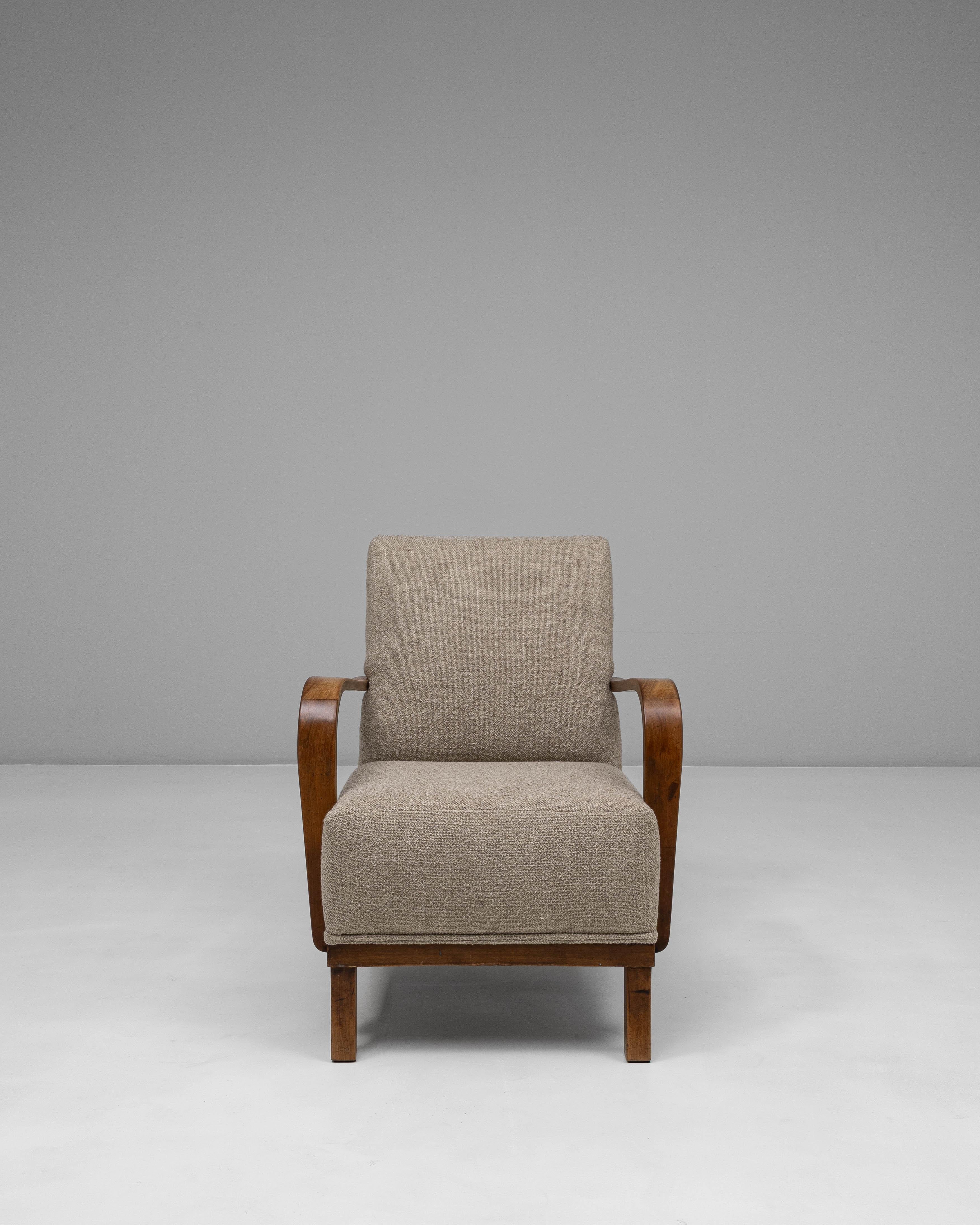 Este sillón tapizado de cóctel francés de los años 40 encarna la relajada sofisticación del diseño de salón de mediados de siglo. Los brazos de madera suavemente curvados, fabricados en madera noble de tonos cálidos, introducen una cualidad fluida y