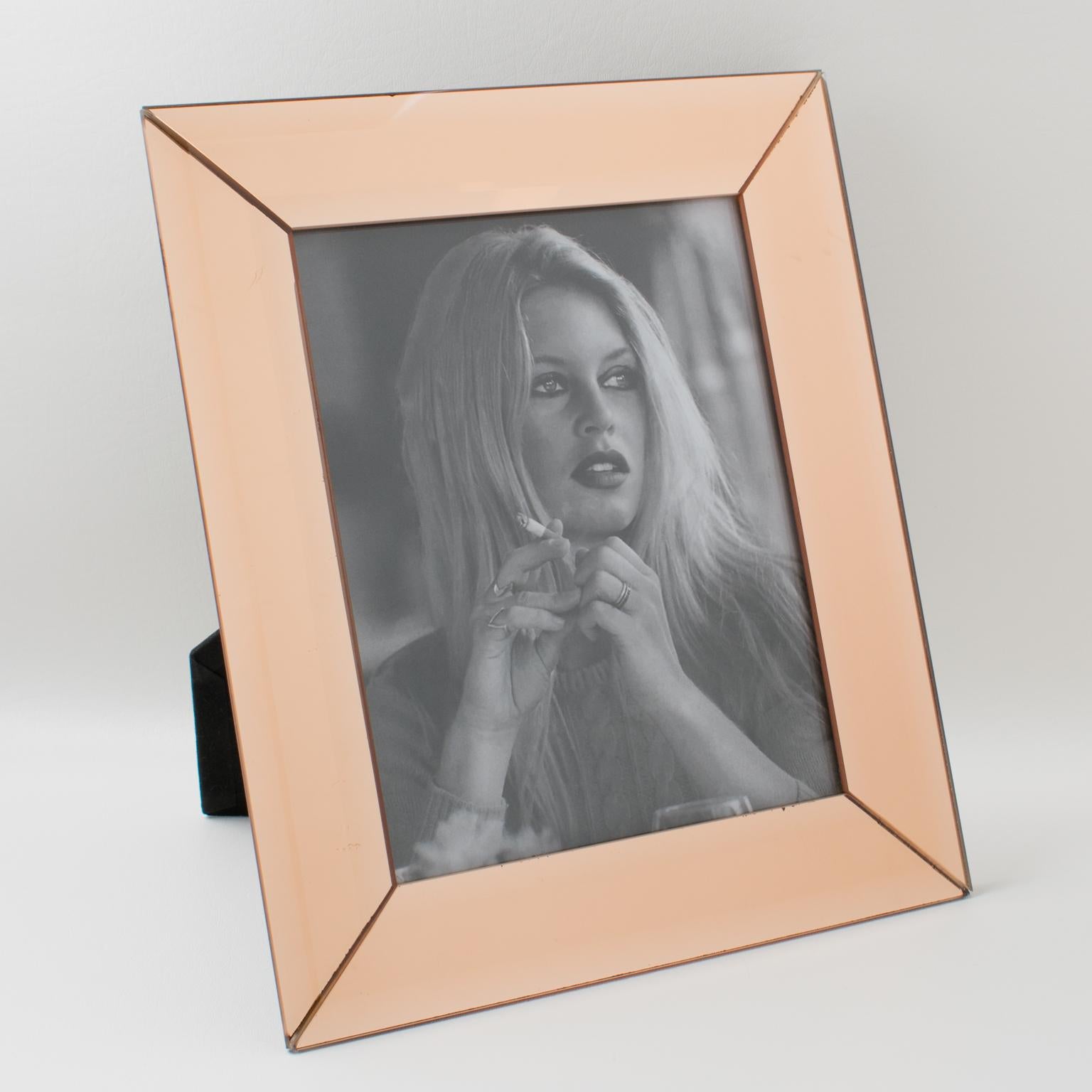 Elegant 1940s French Hollywood Regency mirrored picture photo frame. Deep beveling and large flat faceted sides in lovely copper or pink peach color. Frame can be placed either in portrait or in landscape position. Back and easel in black velvet