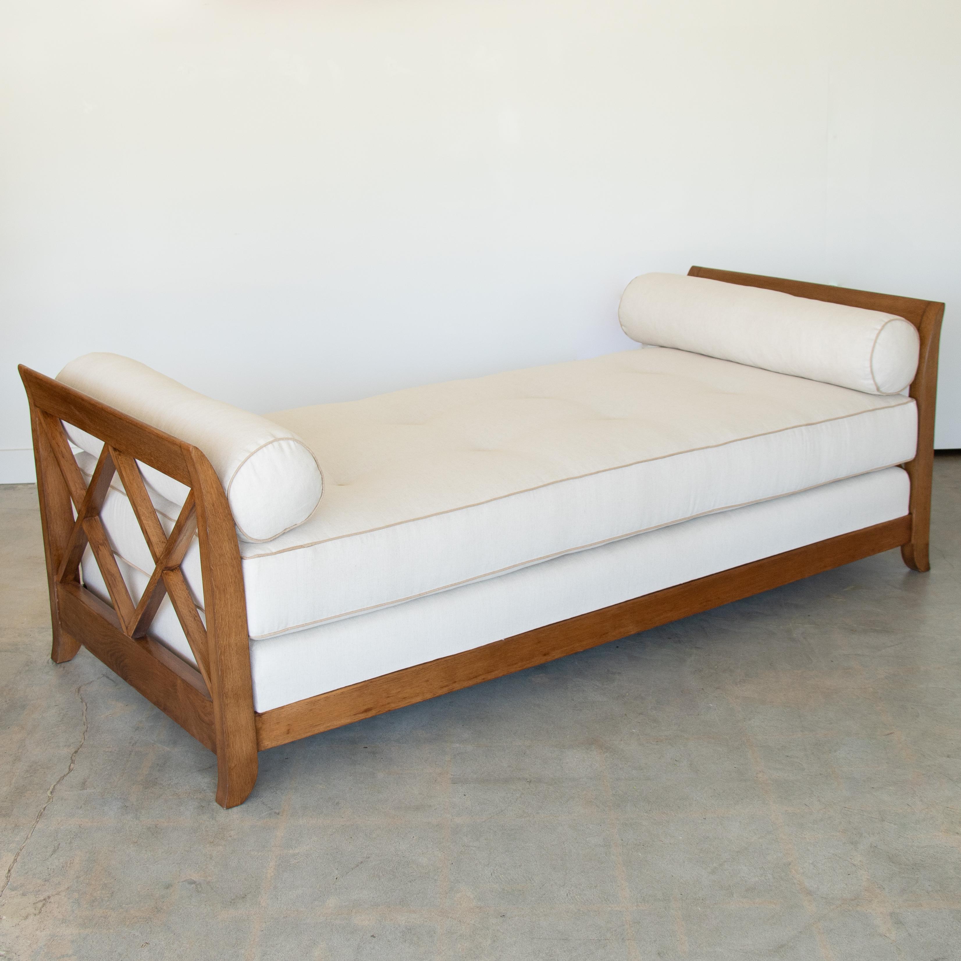 Incredible vintage French daybed in the style of Jean Royère, circa 1940's. Long oak wood frame with croisillon detail. Newly refinished wood showing beautiful natural grain. Newly added cream linen cushion with tan linen trim and button detail.