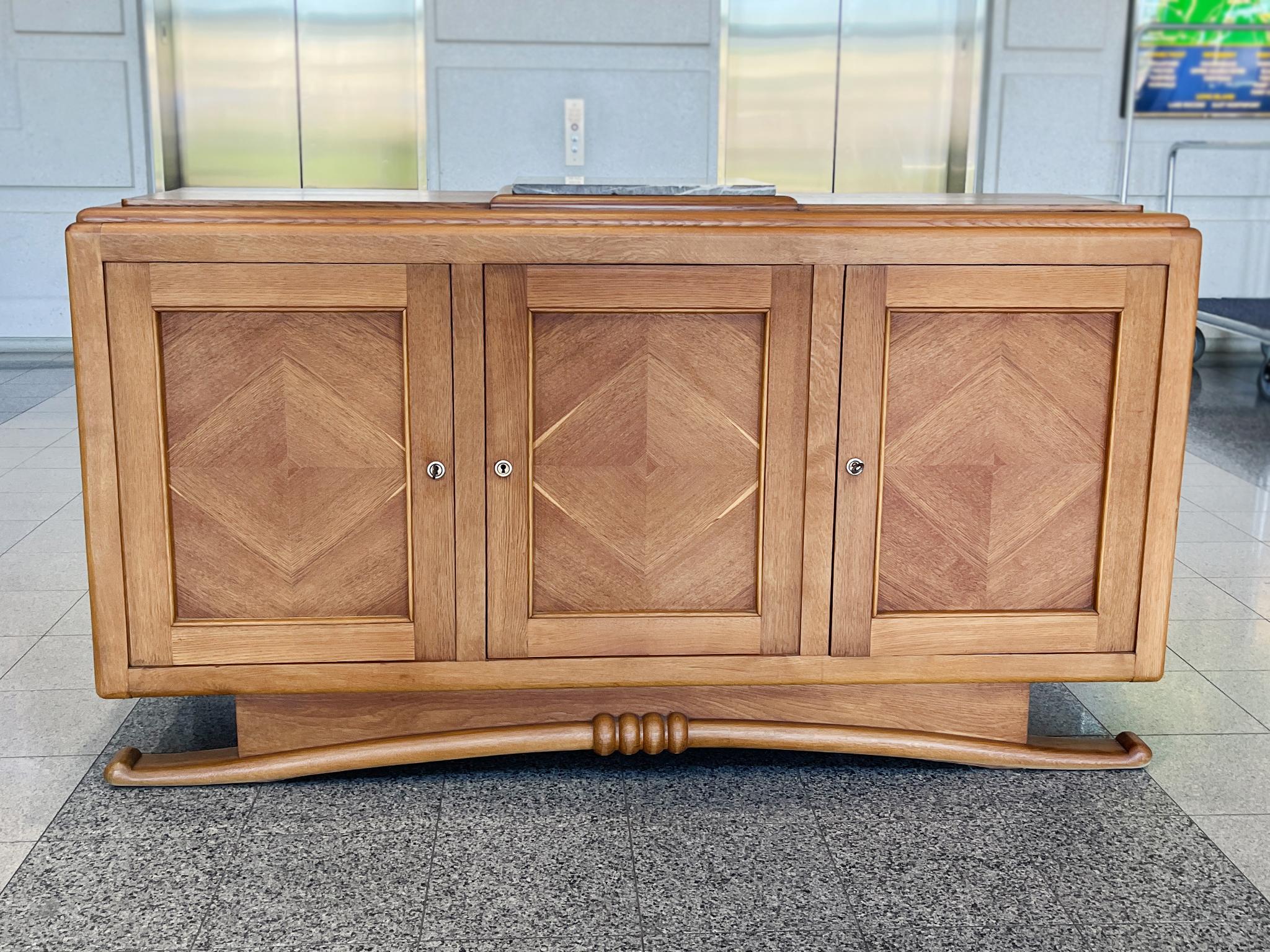 Questa credenza French Deco degli anni '40 si distingue per la sua eccezionale maestria. È realizzato in Oak con un inserto in marmo grigio sul piano del tavolo. Un'elegante combinazione di linee eleganti e bordi arrotondati caratterizza il design