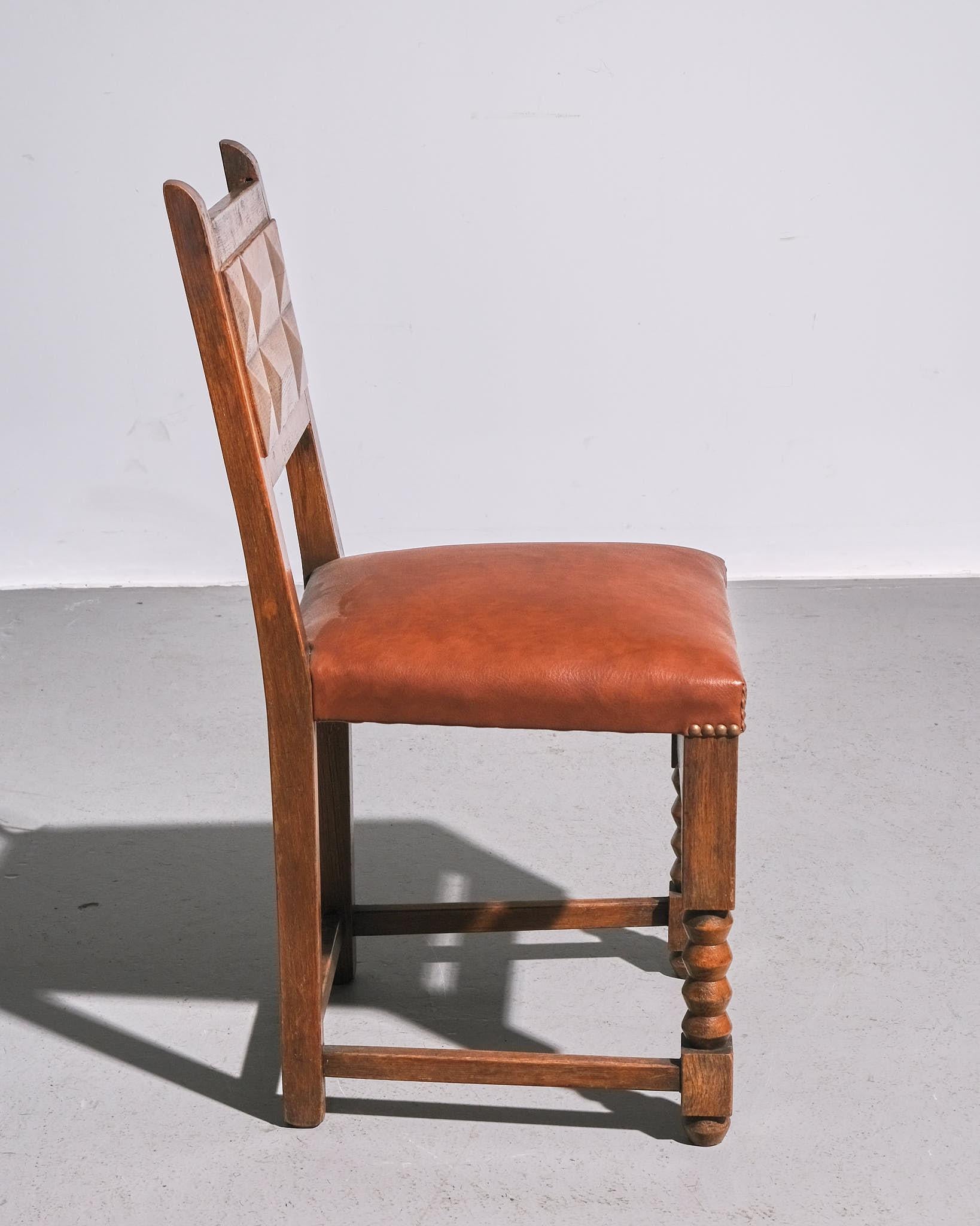 A classic French dining chair from the 1940s, featuring a stained wood frame and tan leather upholstery. The chair’s clean lines and sturdy construction reflect the craftsmanship of the period, while the rich patina of the wood and leather add
