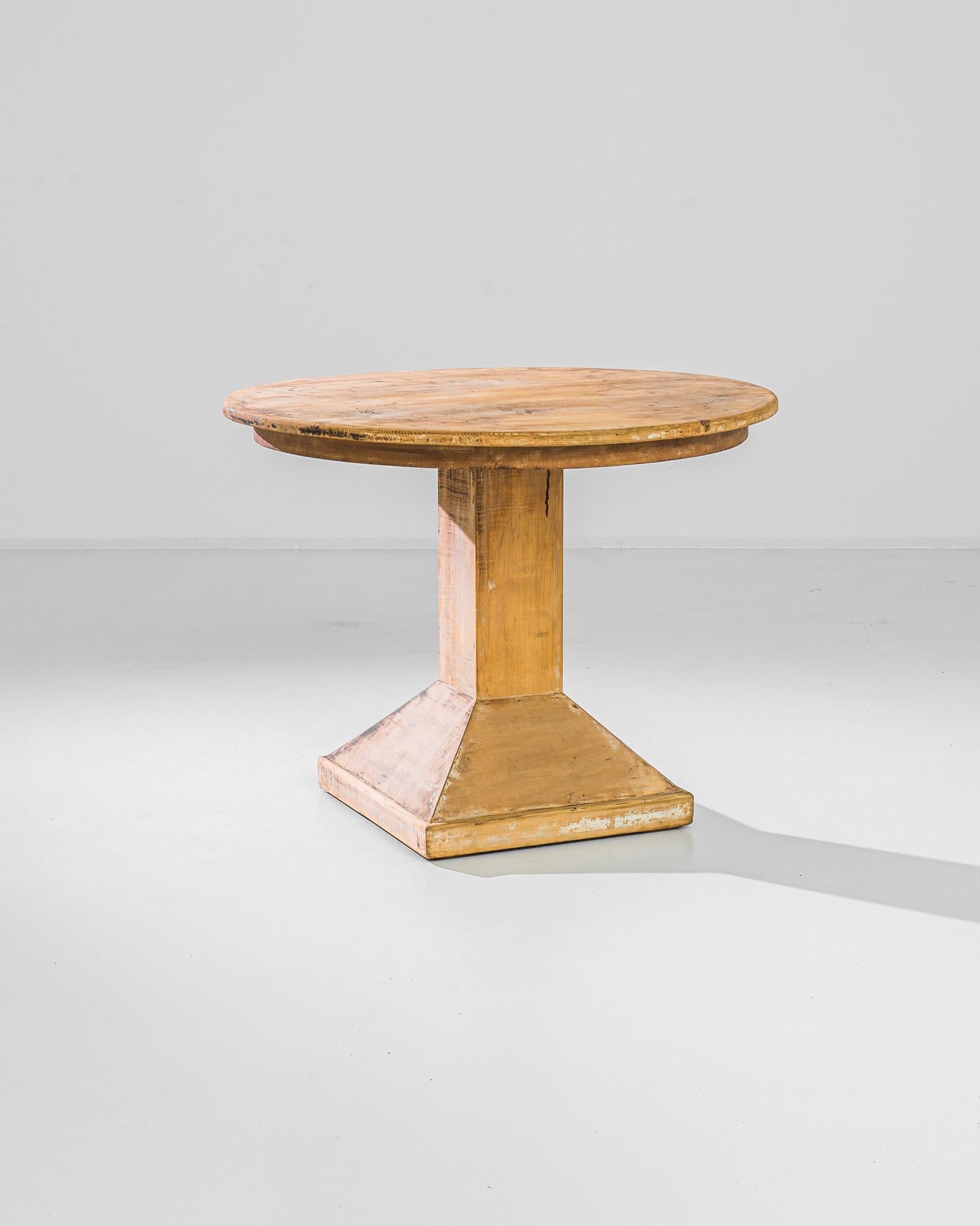 This vintage table made in France circa 1940 presents a perfectly balanced anatomy of geometric shapes: a sturdy triangle base connected with a circular table top by a rectangular leg. The natural wood finish of a light optimistic tone with