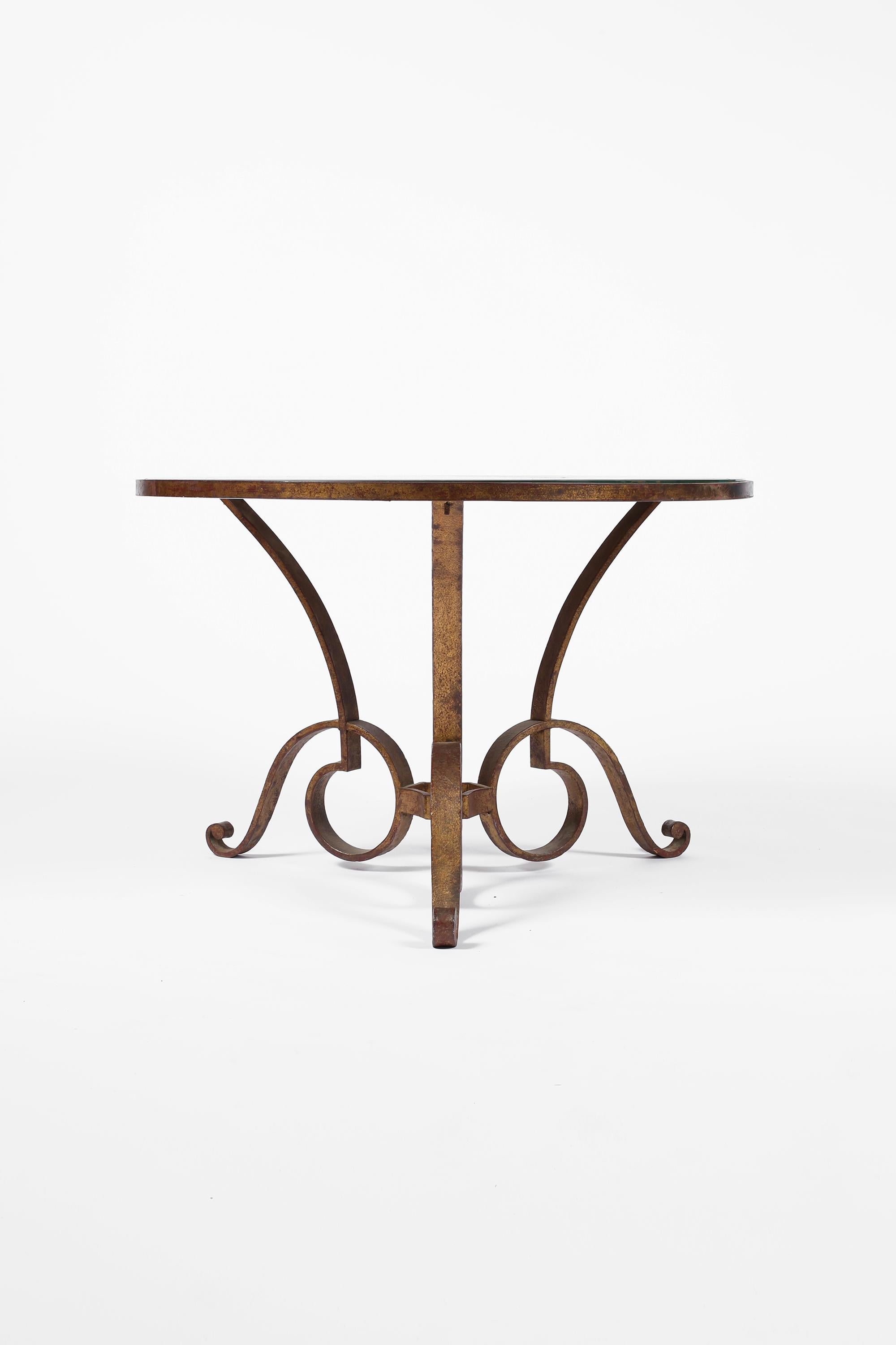 A large circular coffee/side/occasional table by René Drouet (1899-1993), featuring a decorative gilt forged iron frame and beautifully distressed original églomisé glass top. French, circa 1940.