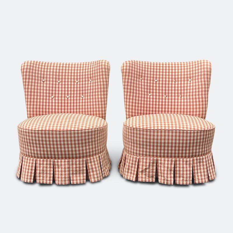 A delightful pair of 1940s French gingham upholstered chairs ?The curved and tapered back sweeps to a generous sprung seat dressed with a subtlety flared pleated skirt, finished with covered buttons and edged with gingham piping.