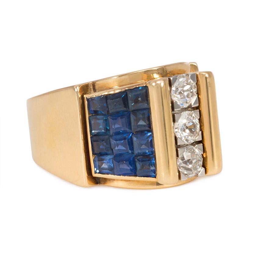 A Retro odeonesque gold, sapphire, and diamond ring, centered by a column of three diamonds flanked by gold scrolls, the shoulders with tapered, invisibly-set sapphires, in 18k and platinum. France. Atw. 0.90 ct. diamonds.

Top center: 1.5 cm wide,