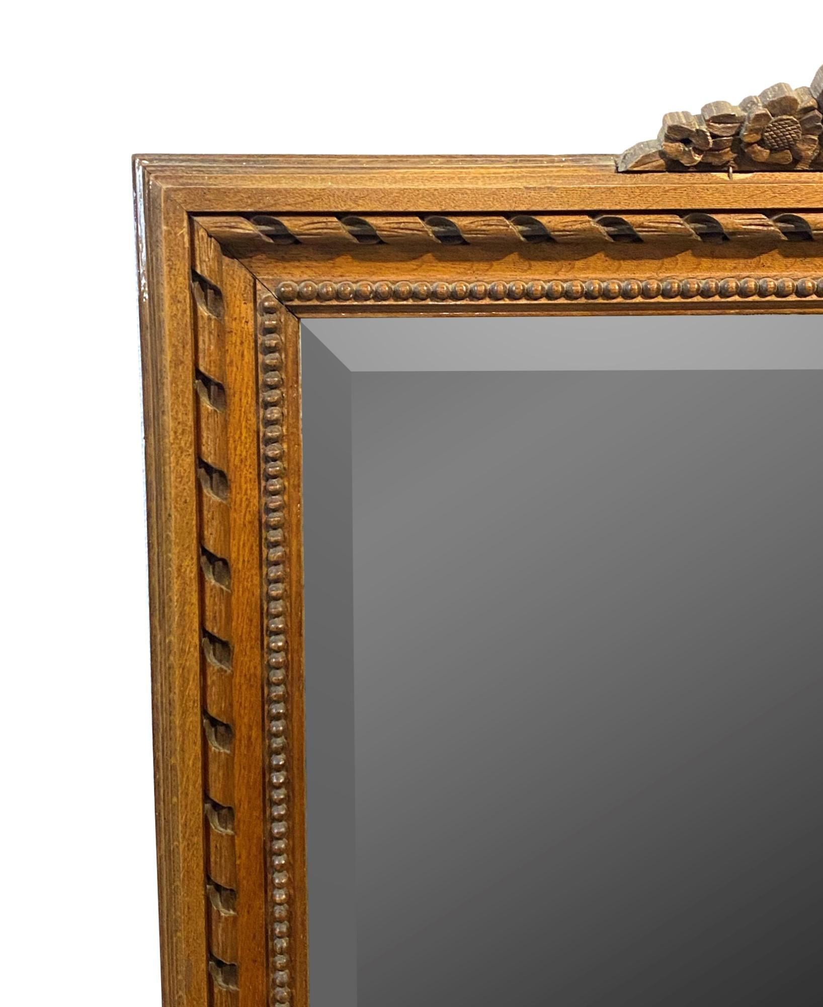 French 1940s hand carved wood frame beveled mirror featuring a floral design at the top. Please note, this item is located in one of our NYC locations.