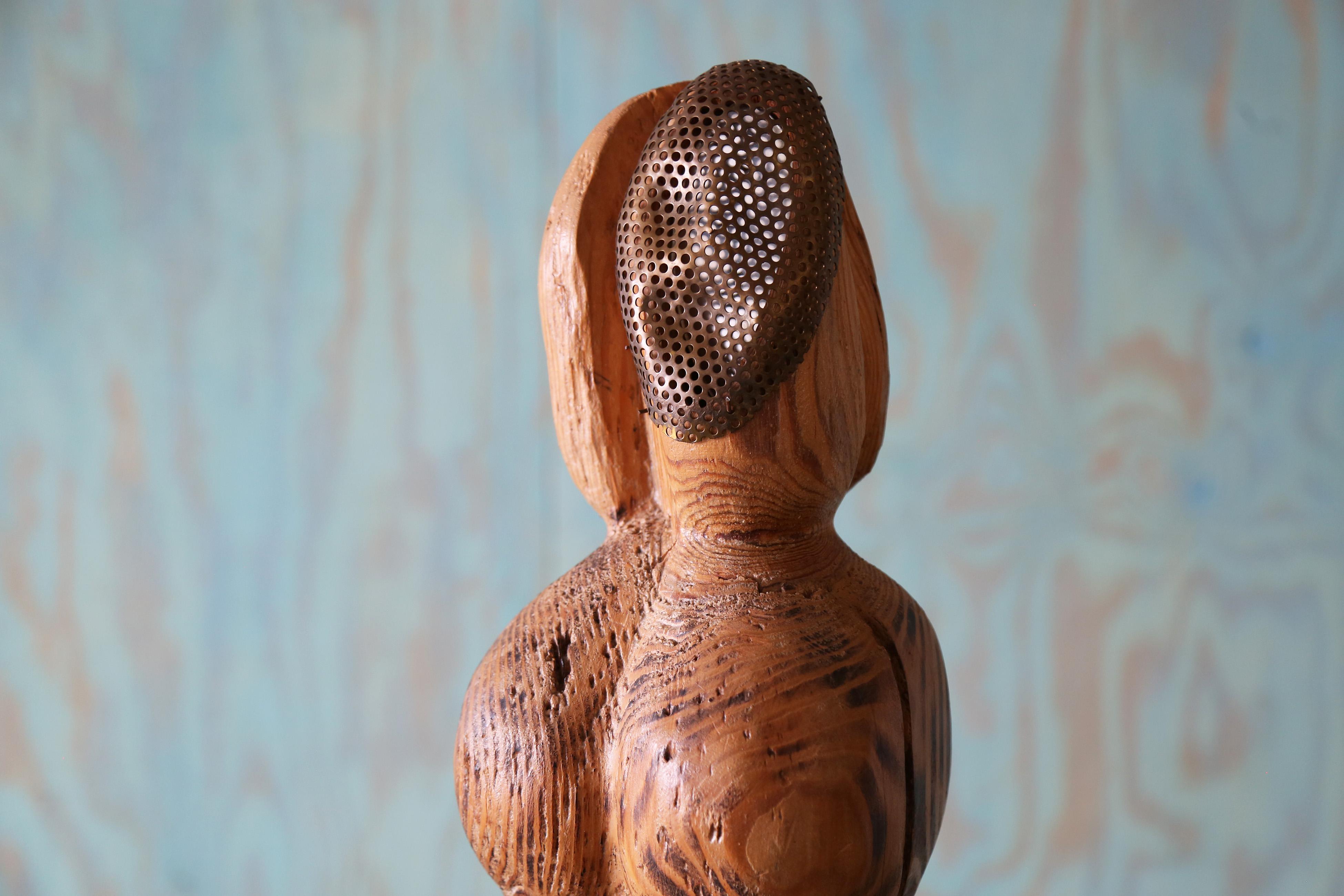 Una lampada francese degli anni '40 con una figura femminile nuda intagliata nel legno. Forma biomorfa con una patina invecchiata sulle venature del legno a vista.   Il volto è caratterizzato da uno schermo metallico perforato con impronte facciali