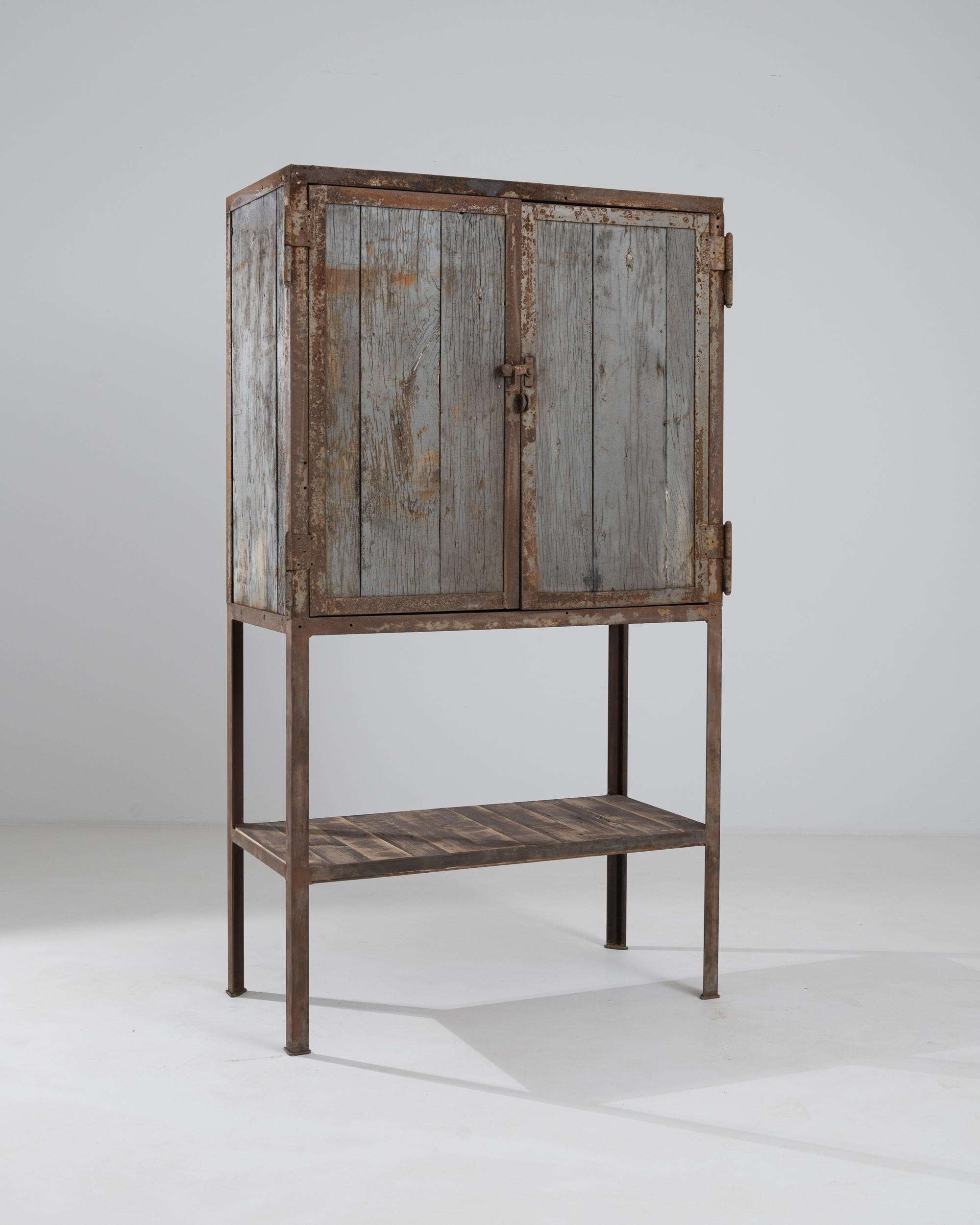 This vintage metal and wooden cabinet combines Industrial practicality with a nostalgic finish. Made in France in the 1940s, a slender but sturdy metal frame elevates the broad wooden cabinet to a convenient height; below, a wooden platform provides