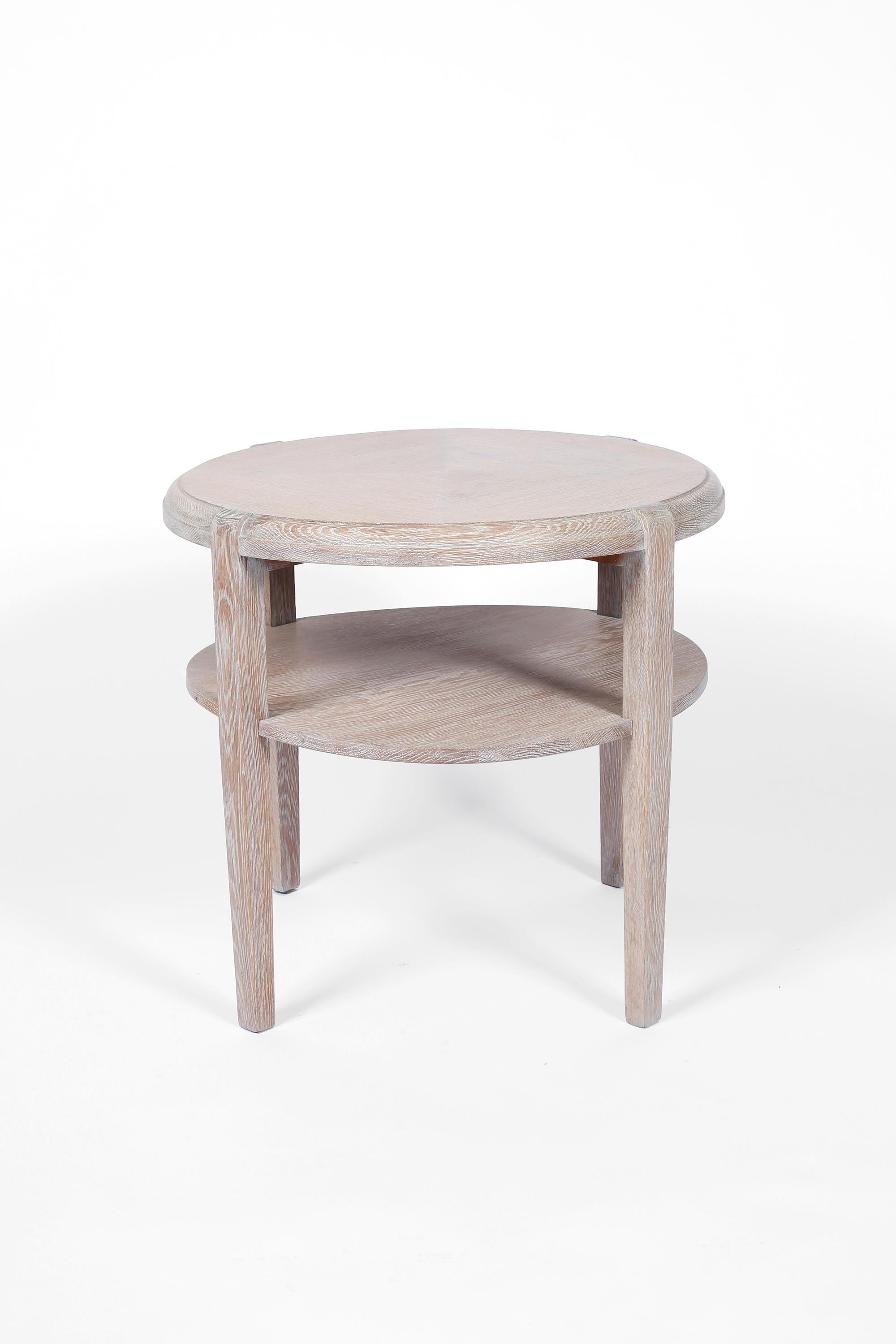 A limed oak two tier circular side table in the manner of Jean-Michel Frank. Constructed from solid oak timber with a decorative veneered top and subtly tapering legs. French, circa  1940s.