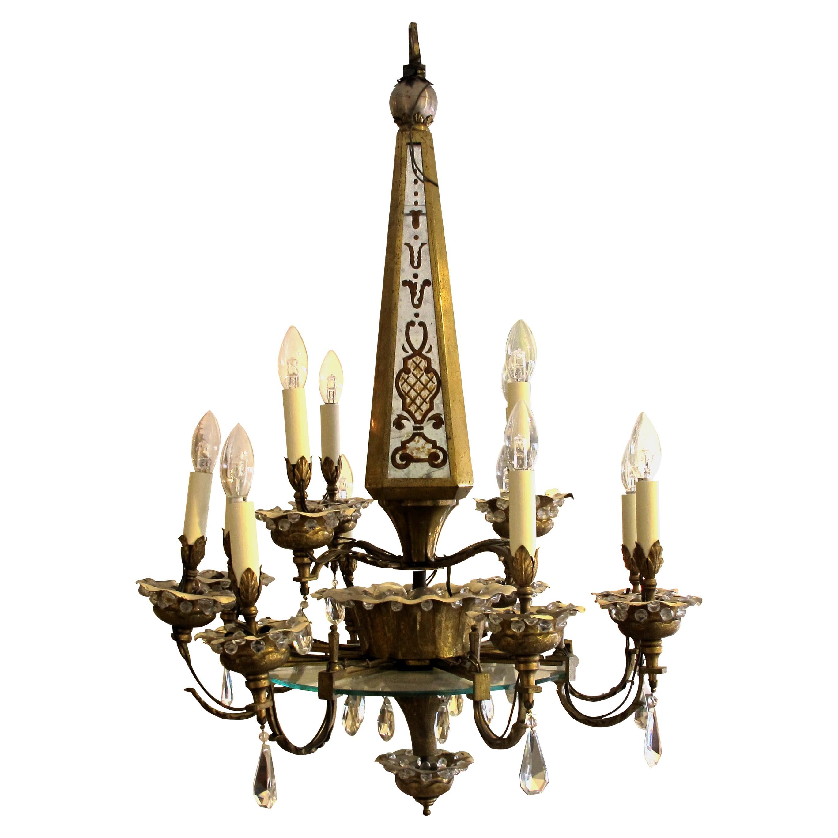 An elegant French Belle Époque twelve-arm Obelisk chandelier by Maison Baguès. This is a Classic gilt metal chandelier from the early 20th century from Maison Baguès with cut glass crystals and églomisé mirrors on the obelisk stem. The twelve arms
