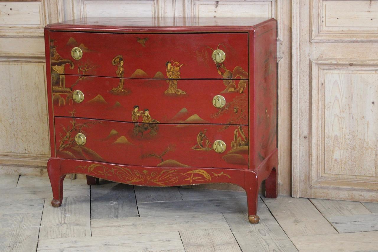 A charming 1940s French red lacquered commode with the original decoration and brass handles.