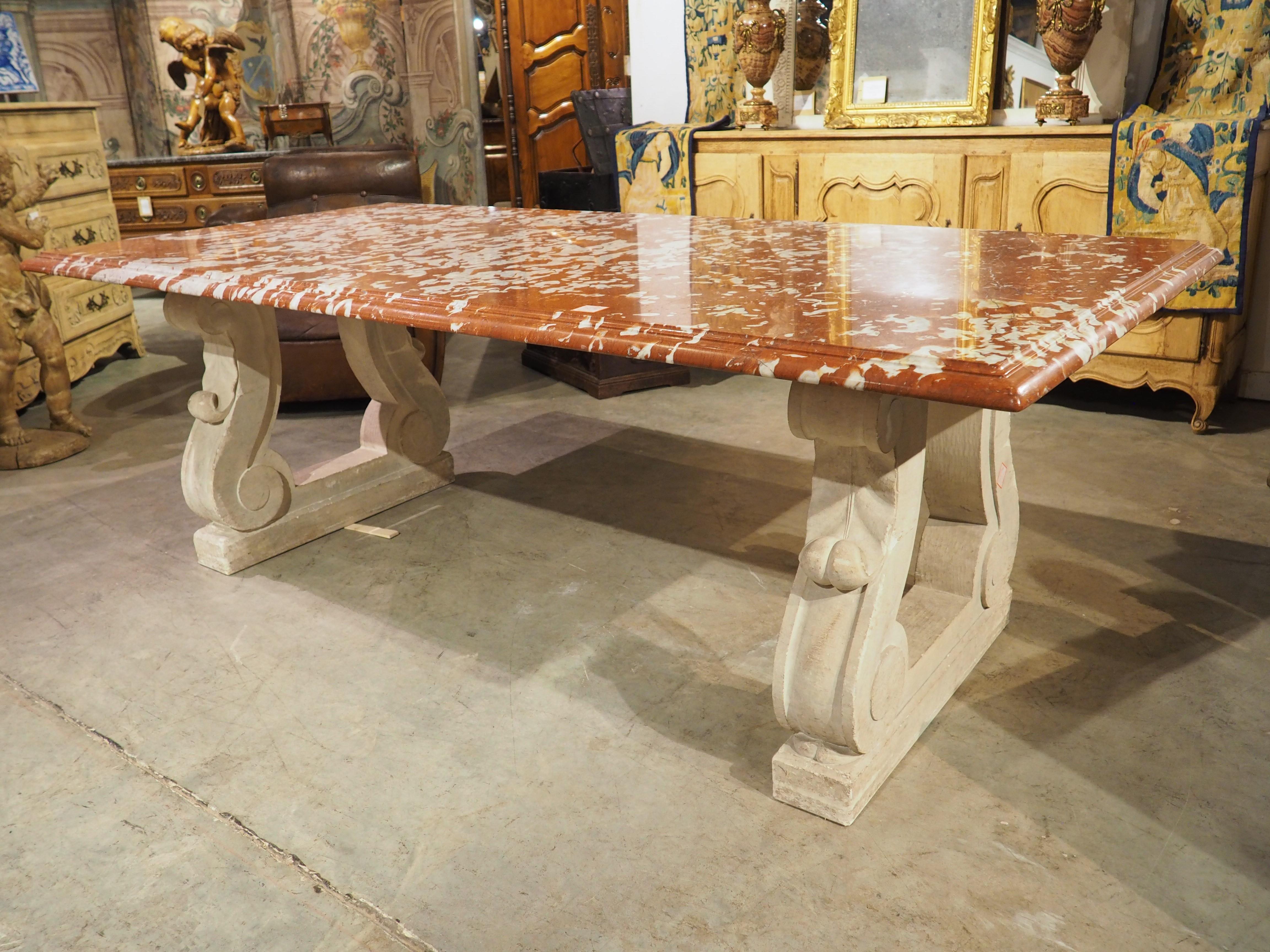 Supported by two thick limestone bases, this beautiful French table (from Paris) is topped by a 1 ¾ inch thick rouge de Languedoc marble. A hand-carved quarter-round edge, surrounding a thin cavetto molding, enhances the mottled appearance of the