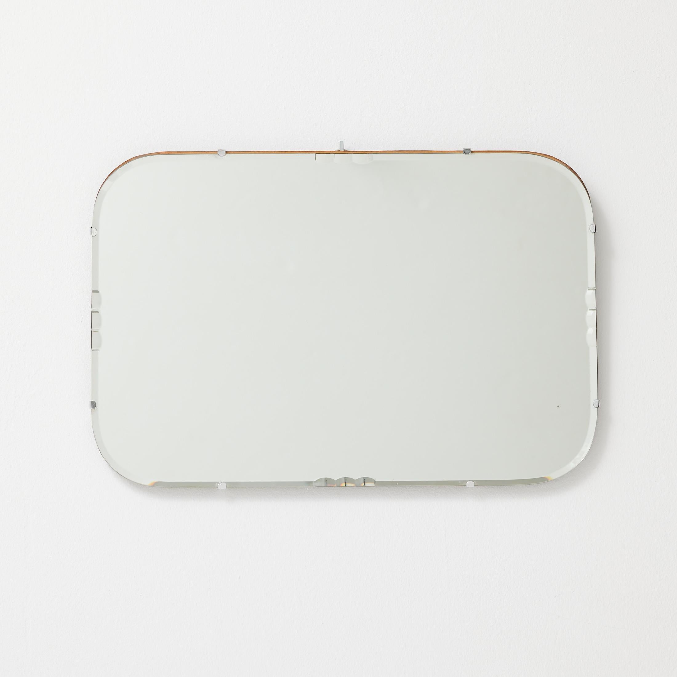 A charming and authentic French wall mirror from the 1940s, retaining its original glass, metal frame, and hanging chain. The mirror features a minimalist rectangular form with gently rounded corners and a discreet patina throughout, testifying to