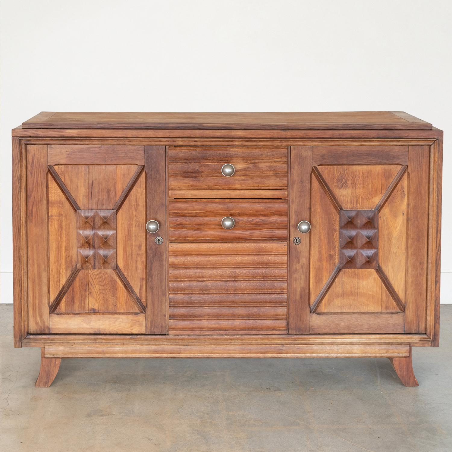 Incredible wood sideboard in the style of Charles Dudouyt from France, 1940's. Beautiful carved wood squares on cabinet doors and chunky curved legs. Large round silver knobs add bold contrast. Cabinet doors on each end open to a single shelf for