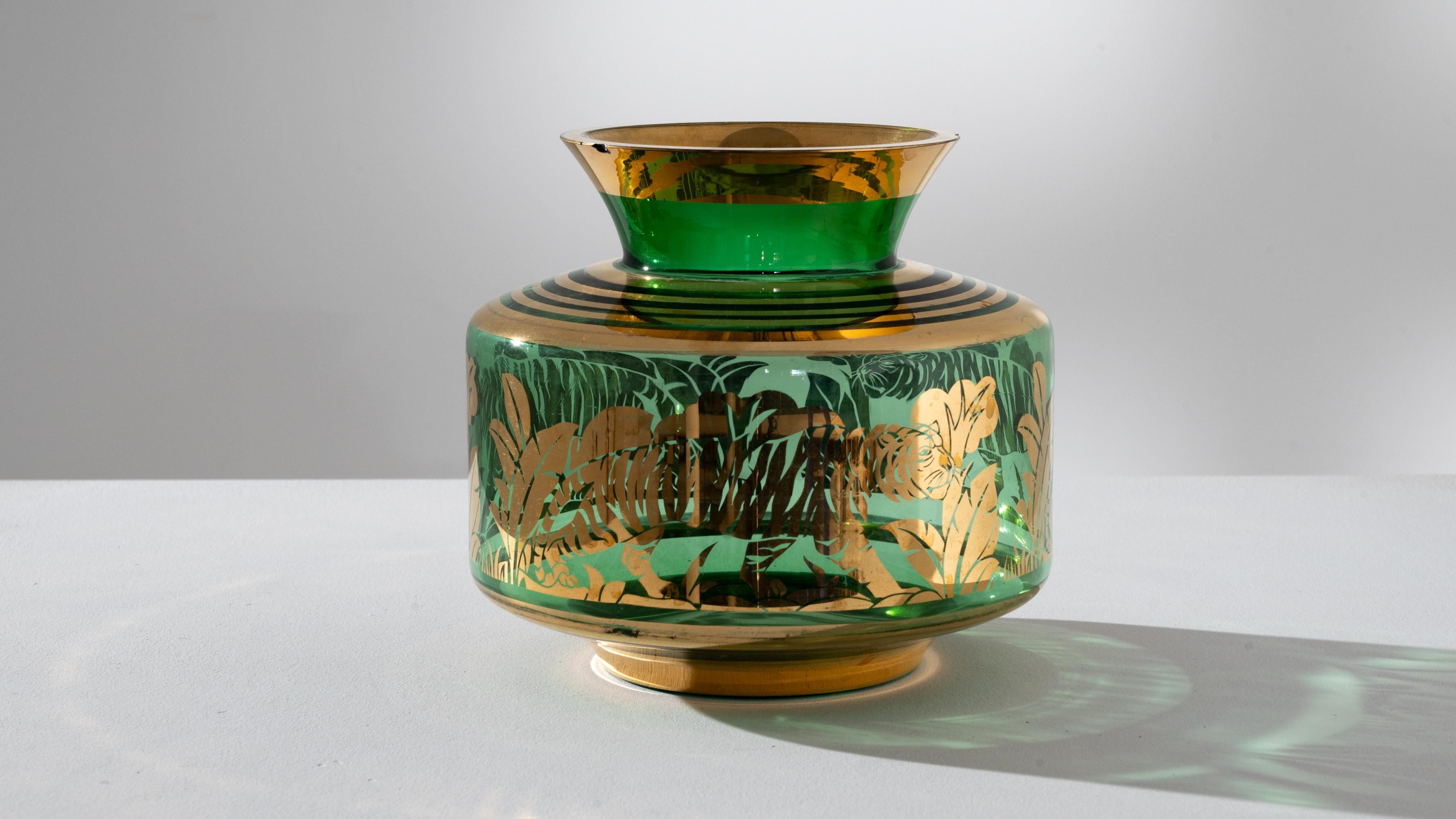 Elevate your space with the captivating allure of this 1940s French Tiger Glass Vase. The rich green hue of the vase, adorned with luxurious gold accents, transports you to an exotic setting. Intricate gold designs depict a majestic tiger gracefully
