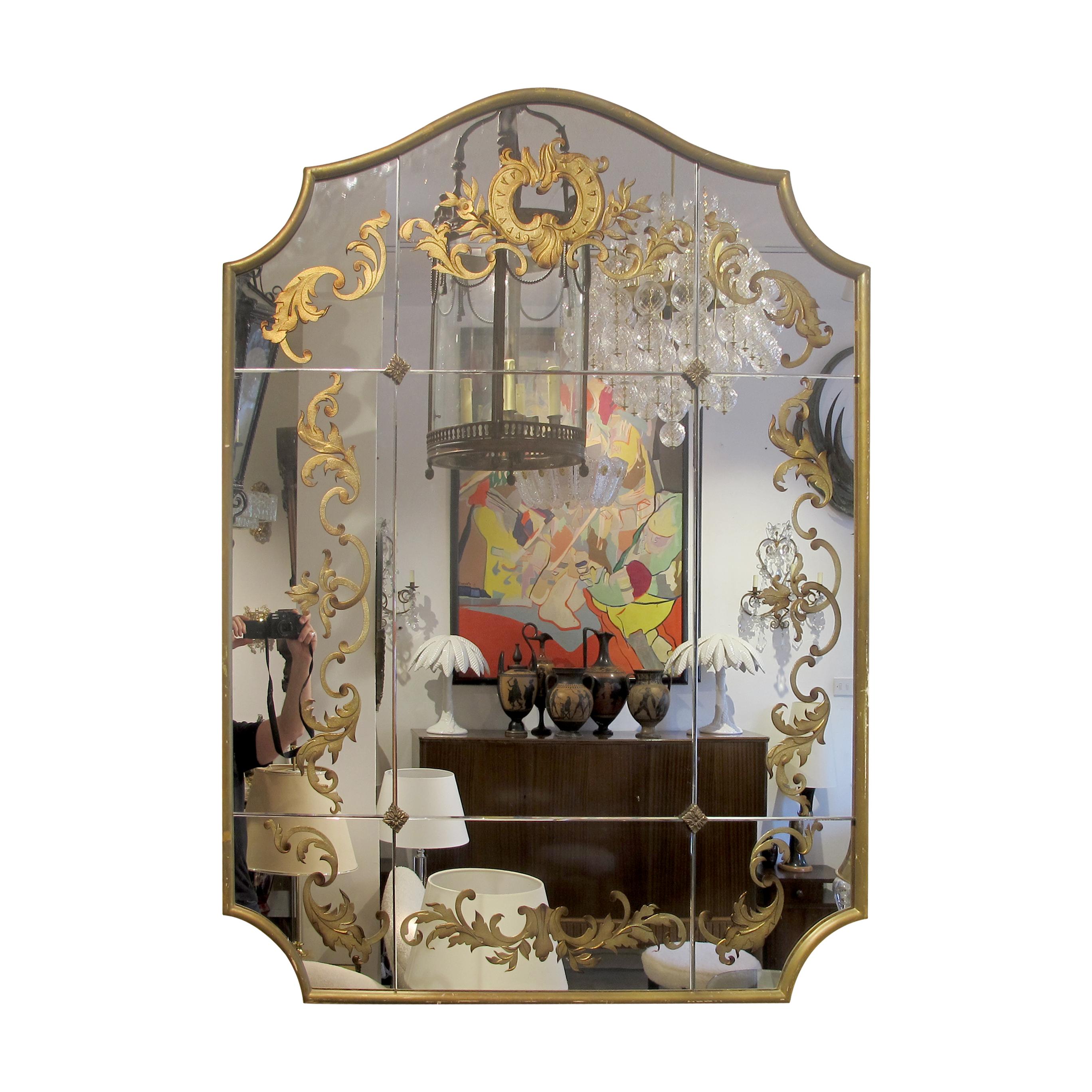 Elegante specchio francese degli anni '40 racchiuso in una cornice dorata in Wood. Lo specchio è composto da nove lastre individuali, meticolosamente tenute insieme da ornati raccordi in ottone. Il design a foglie d'oro eglomisé è di buona qualità e