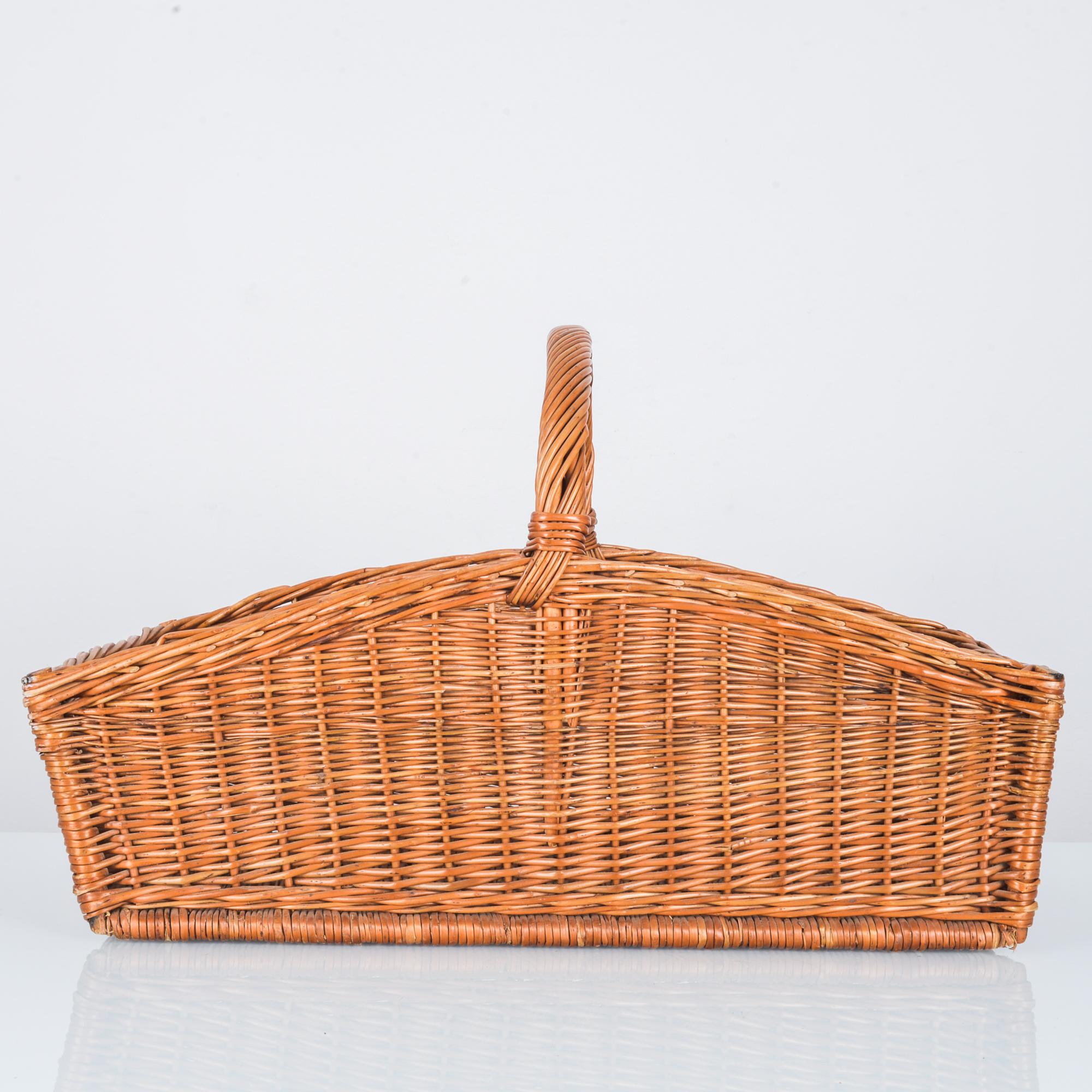 A wicker basket from France, circa 1940. A cheerful rustic piece-- ample yet light, the shape is crowned by a broad arch. The woven wicker has a bright, coppery tone. A handle of twisted wicker allows the basket to be carried over the elbow for