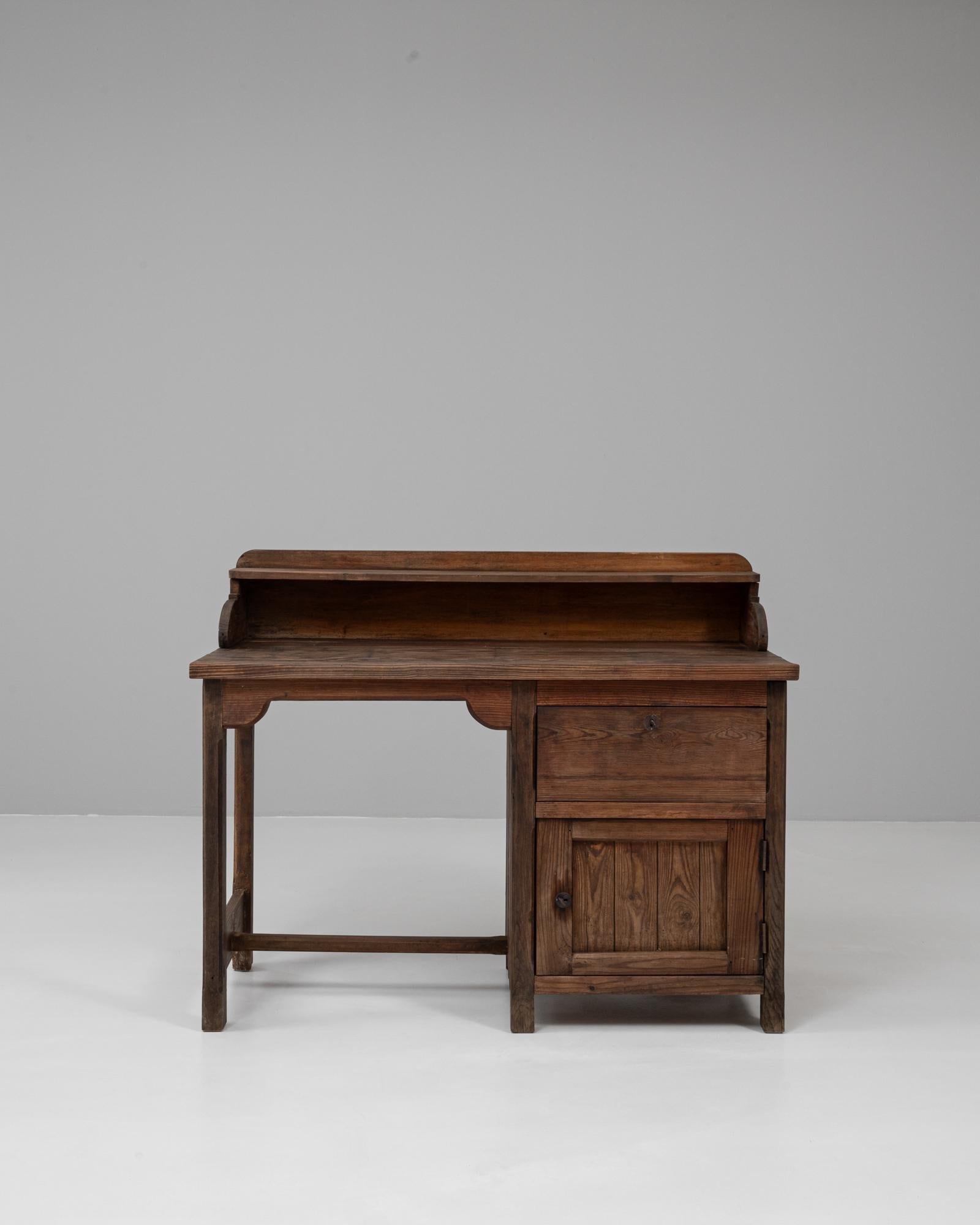 Dieser französische Holzschreibtisch aus den 1940er Jahren besticht durch sein zweckmäßiges, aber dennoch charmantes Design, bei dem Funktionalität und Langlebigkeit im Vordergrund stehen. Er ist aus Massivholz mit einer warmen, abgenutzten Patina