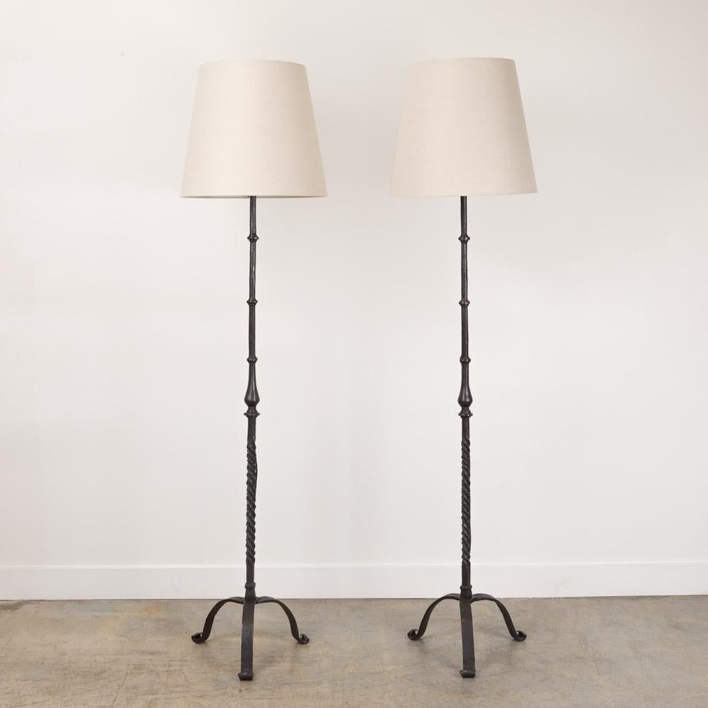 Great vintage heavy iron floor lamp from France, 1940s. Thick iron stem with carved twisted detail on a arched three leg base. Newly rewired with new tapered linen shade. Original iron finish shows nice age and patina. Two available, sold