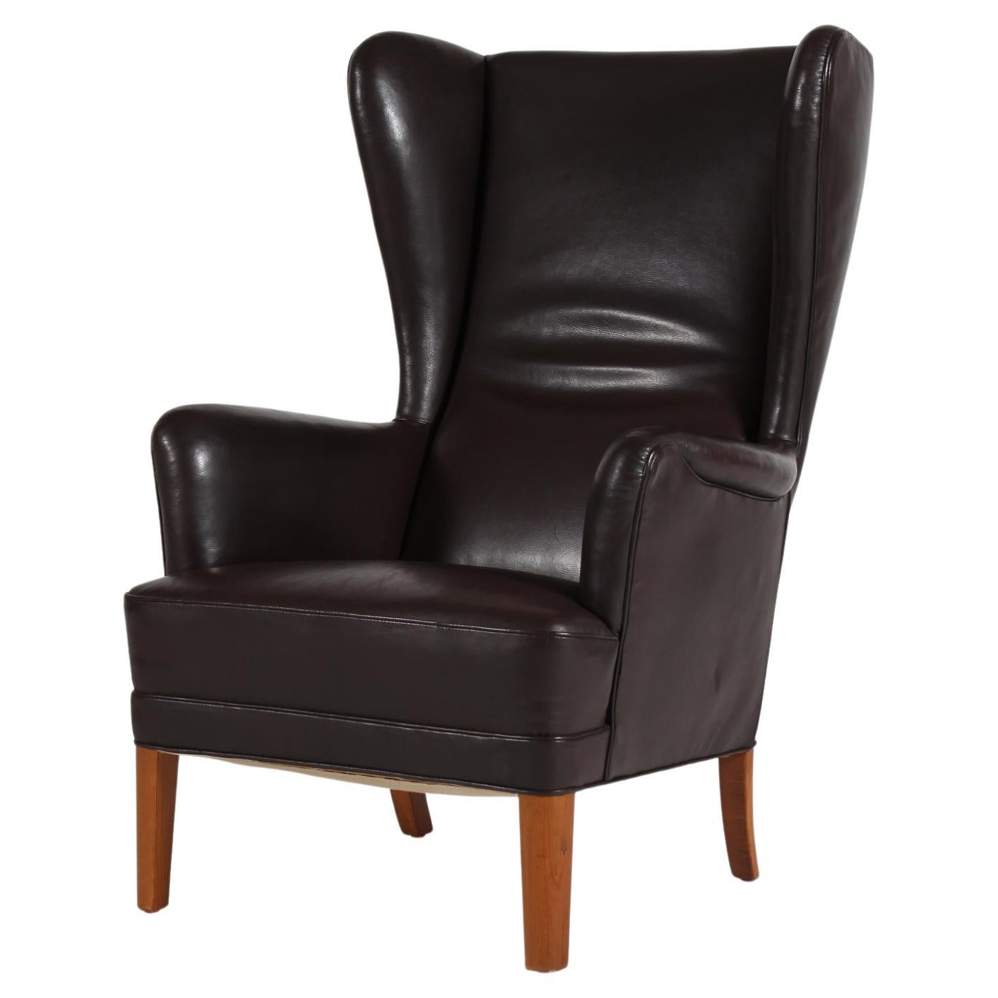 Dänischer moderner Ohrensessel, wahrscheinlich von Fritz Hansen A/S in Dänemark in den 1930-1950er Jahren hergestellt 
Der bequeme Stuhl ist mit mokkabraunem Leder mit Patina gepolstert.

Der von gut ausgebildeten Tischlern und Polstern